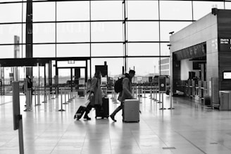 People walk through an airport terminal with luggage.