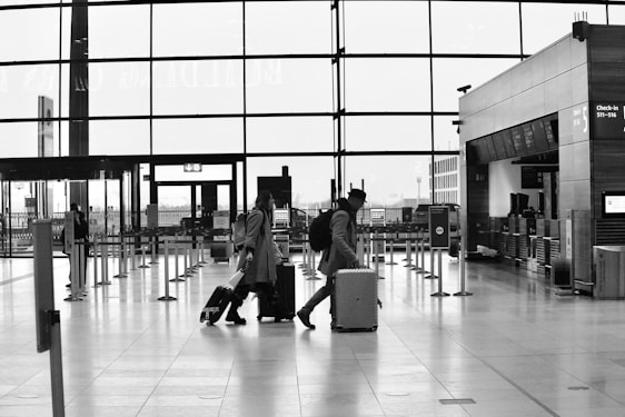 People walk through an airport terminal with luggage.