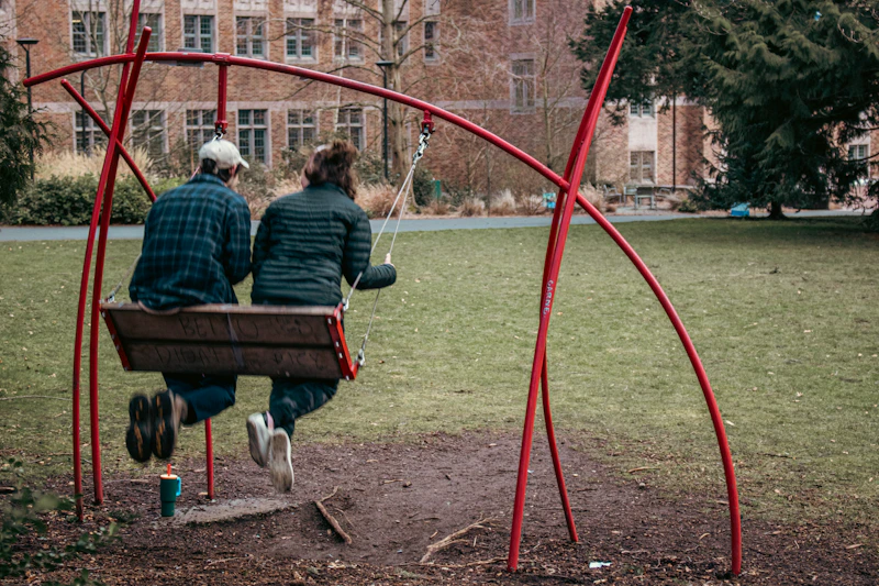 A couple swings on a red, unique swing set.