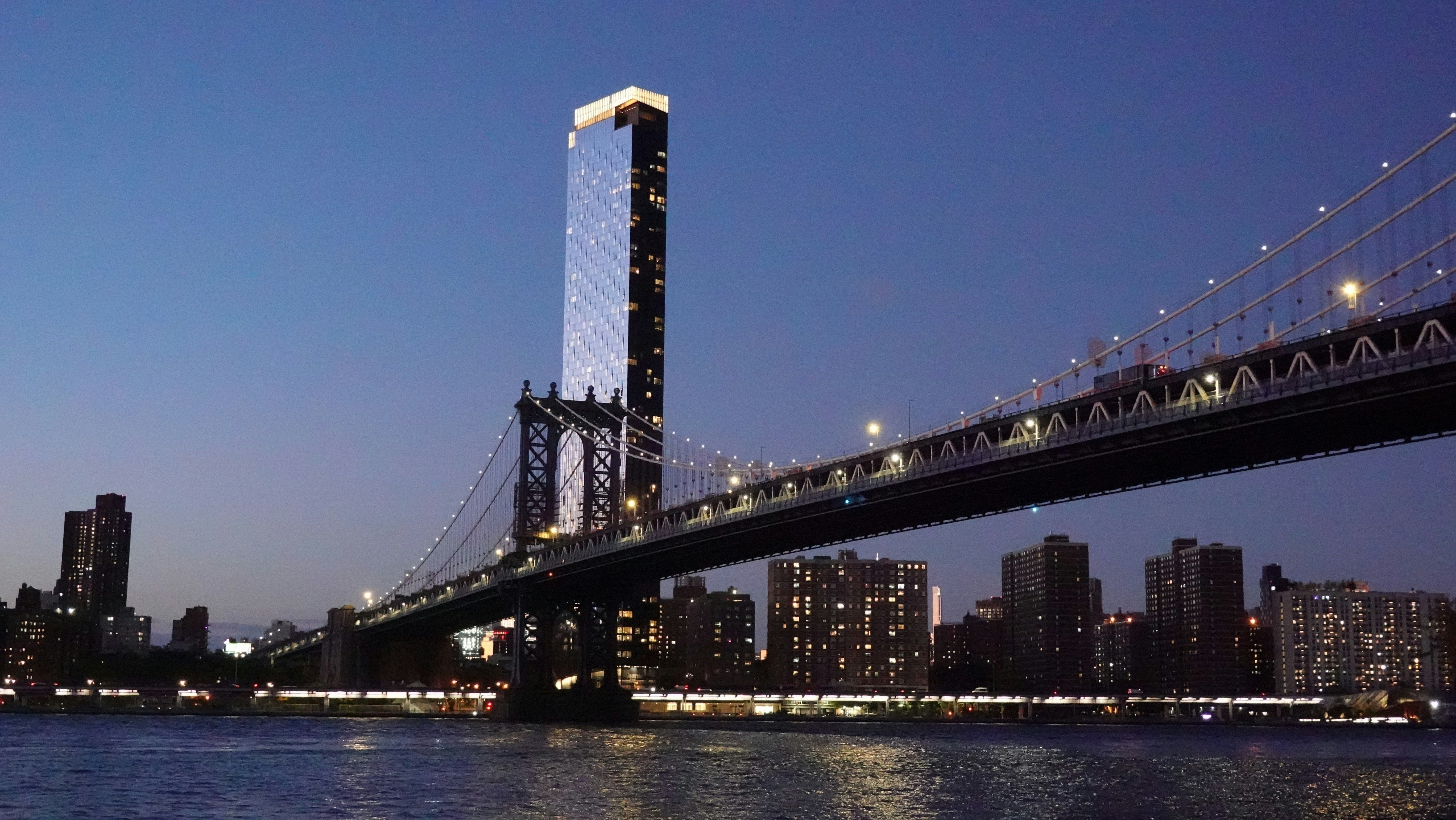 Brücke bei Nacht mit der Skyline der Stadt und dem hohen Gebäude.