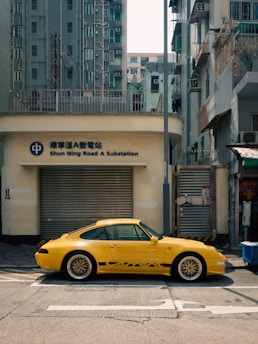 Yellow porsche parked on a city street.
