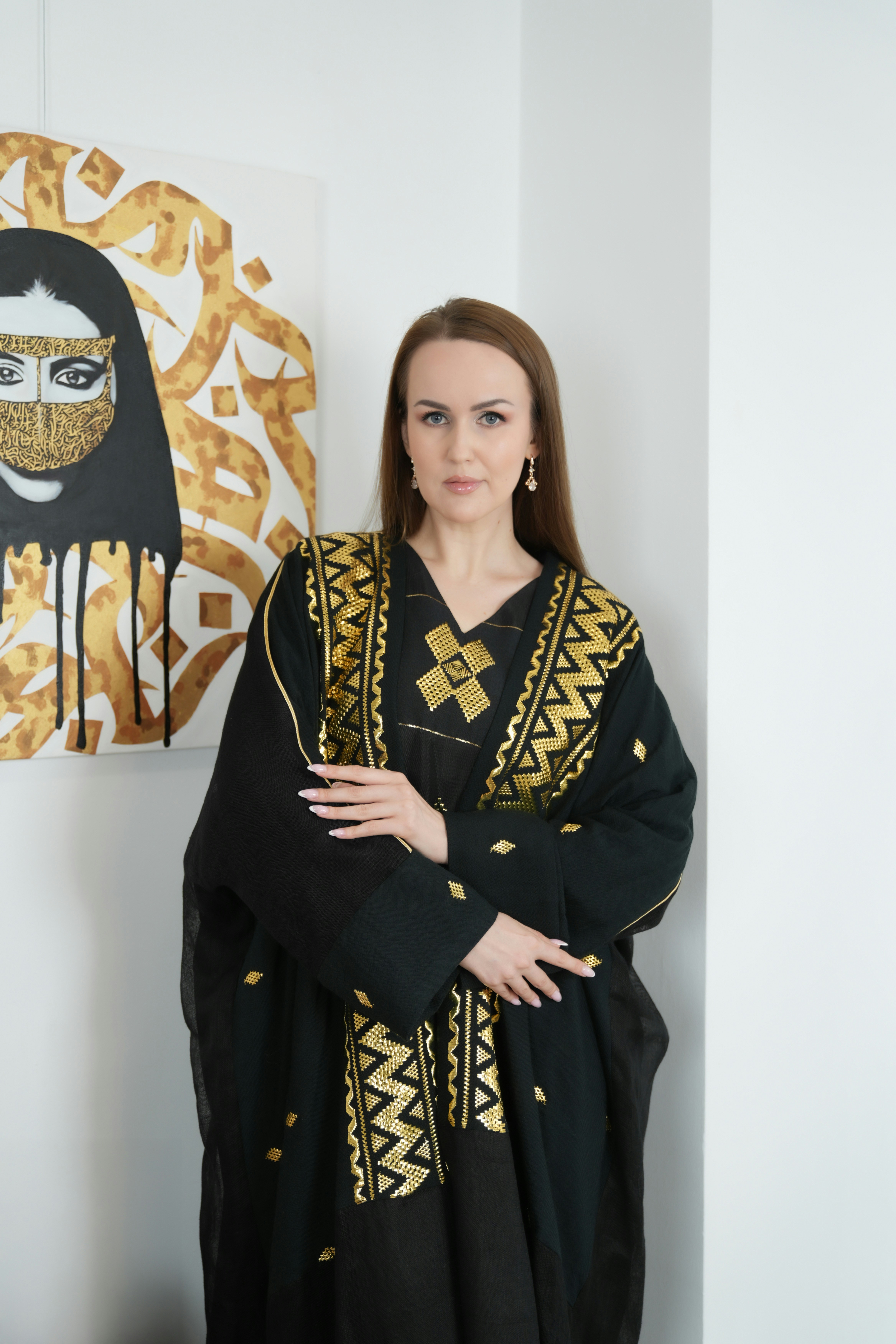 Wanita bergaun hitam berdiri di samping karya seni.