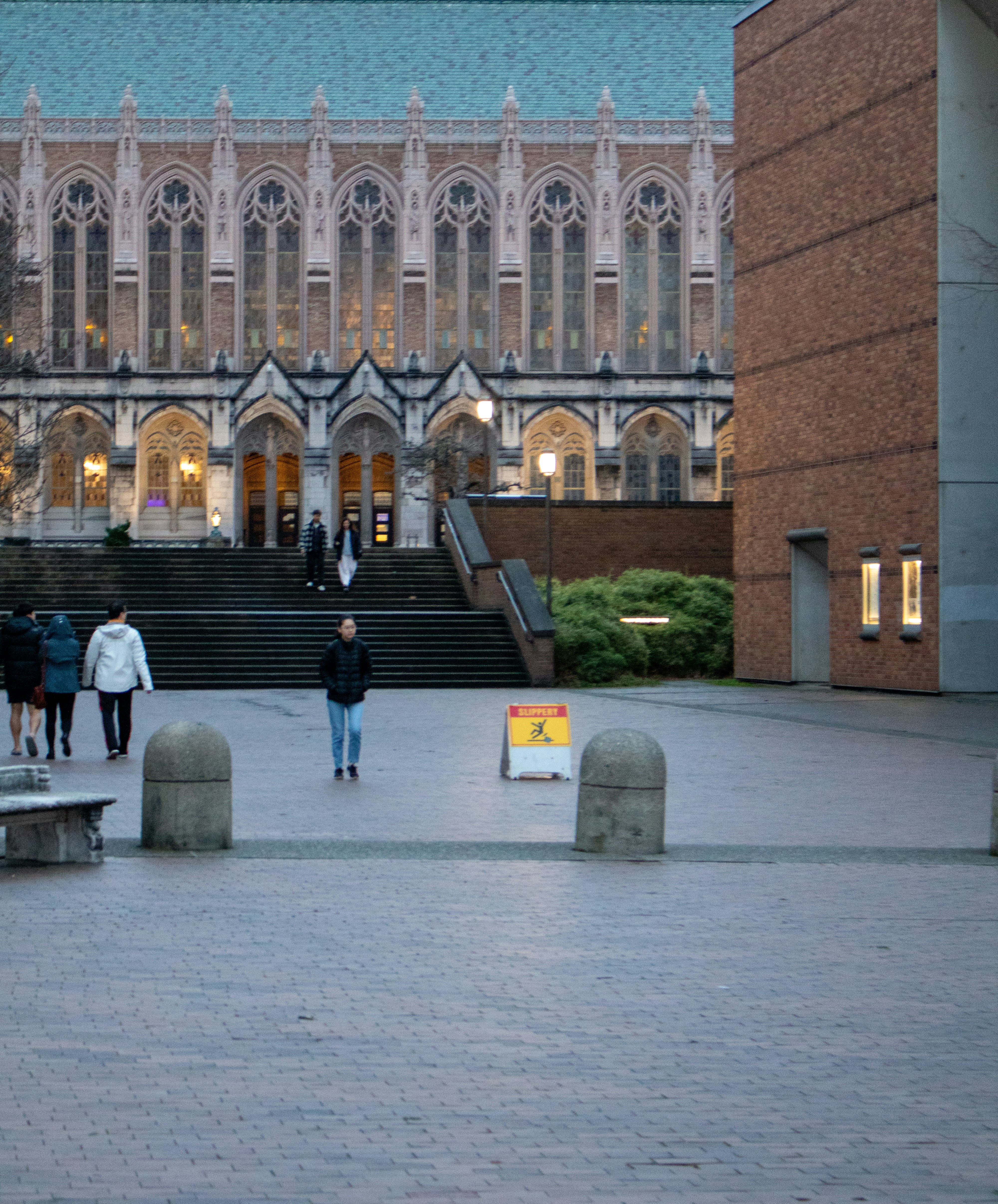 People walk across a courtyard in front of a building.