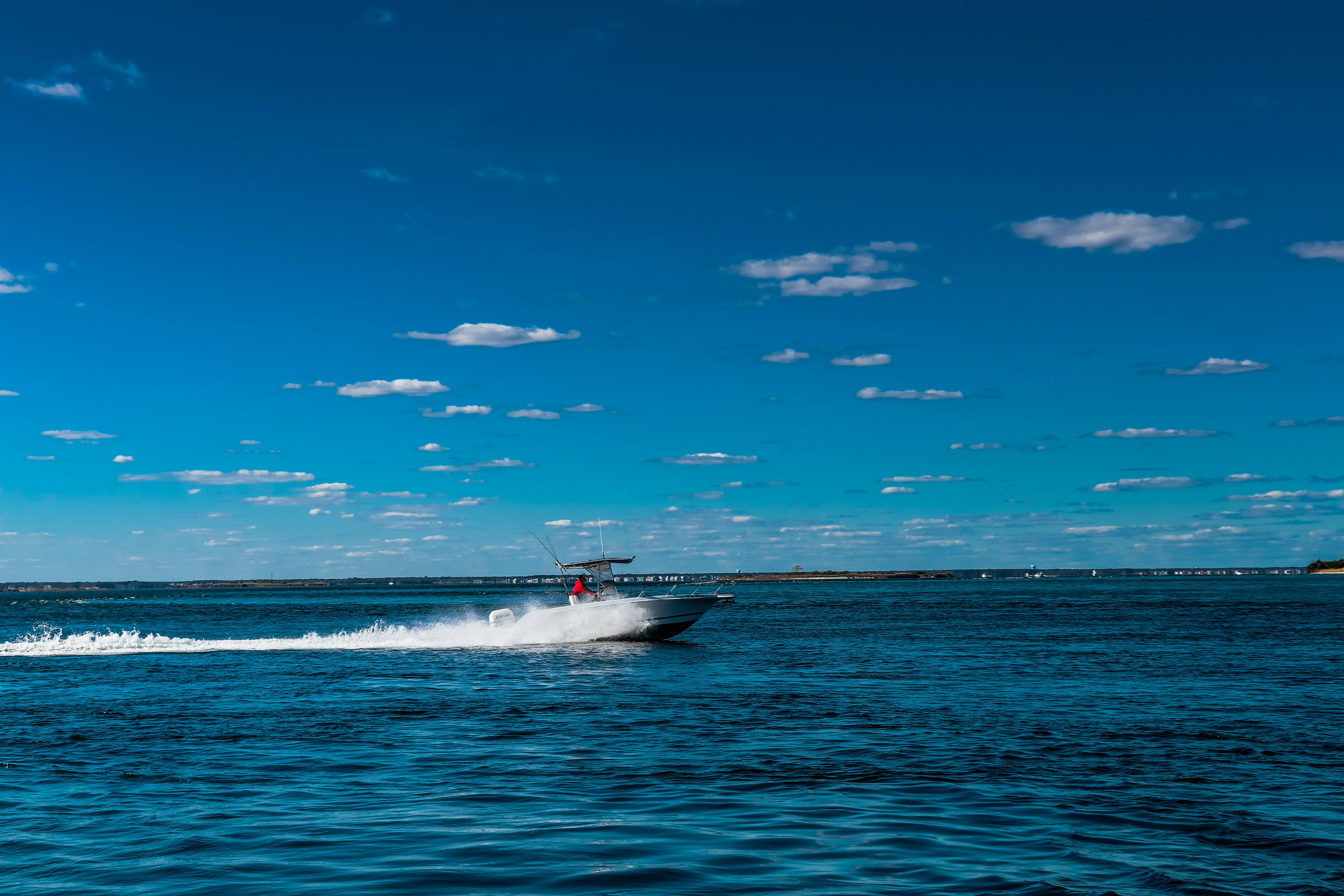 A boat speeds across the blue water.