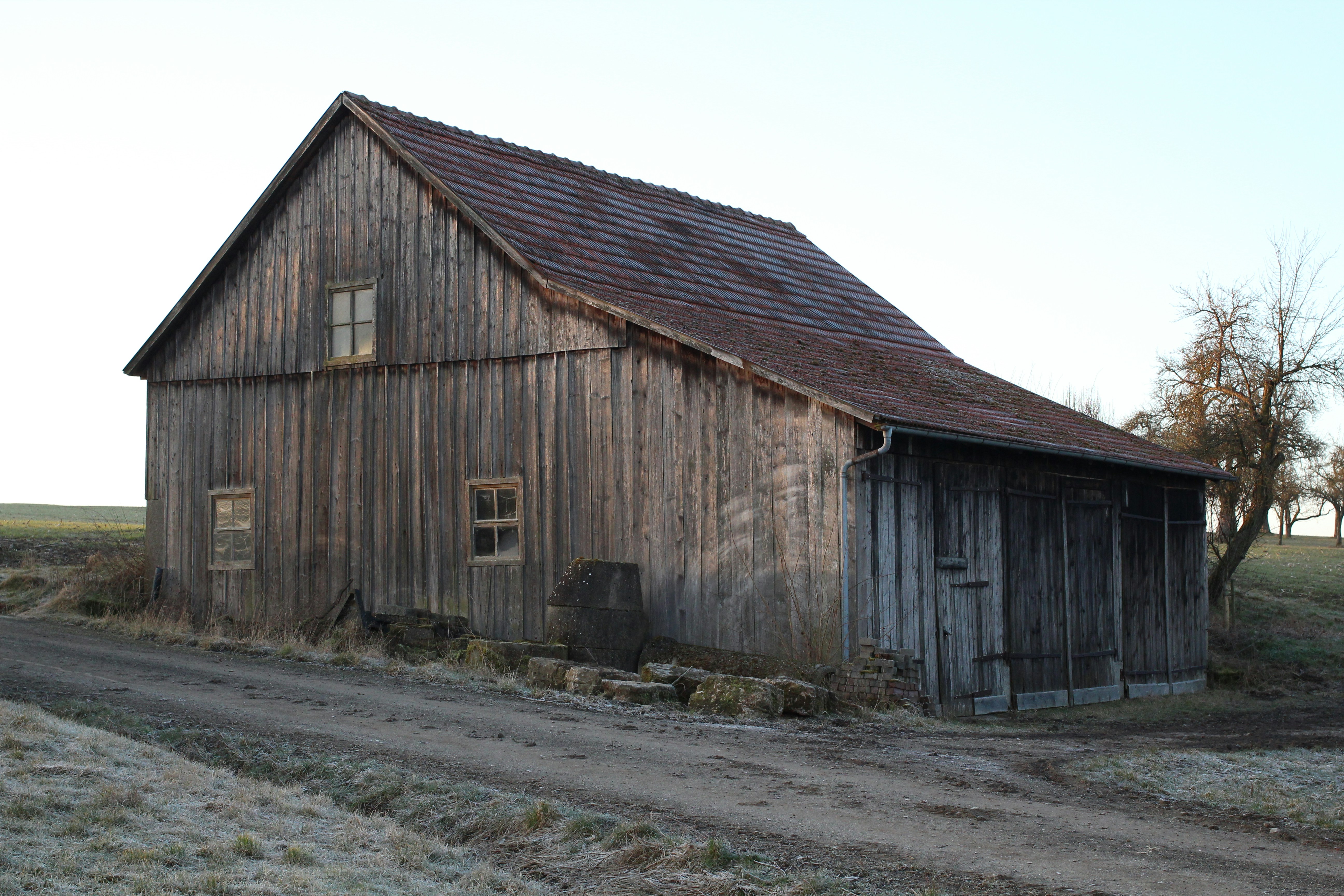 Old weathered barn sits on a dirt road.