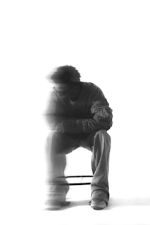 A man sits, blurred, in black and white.