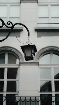 An ornate lamp hangs in front of a building.