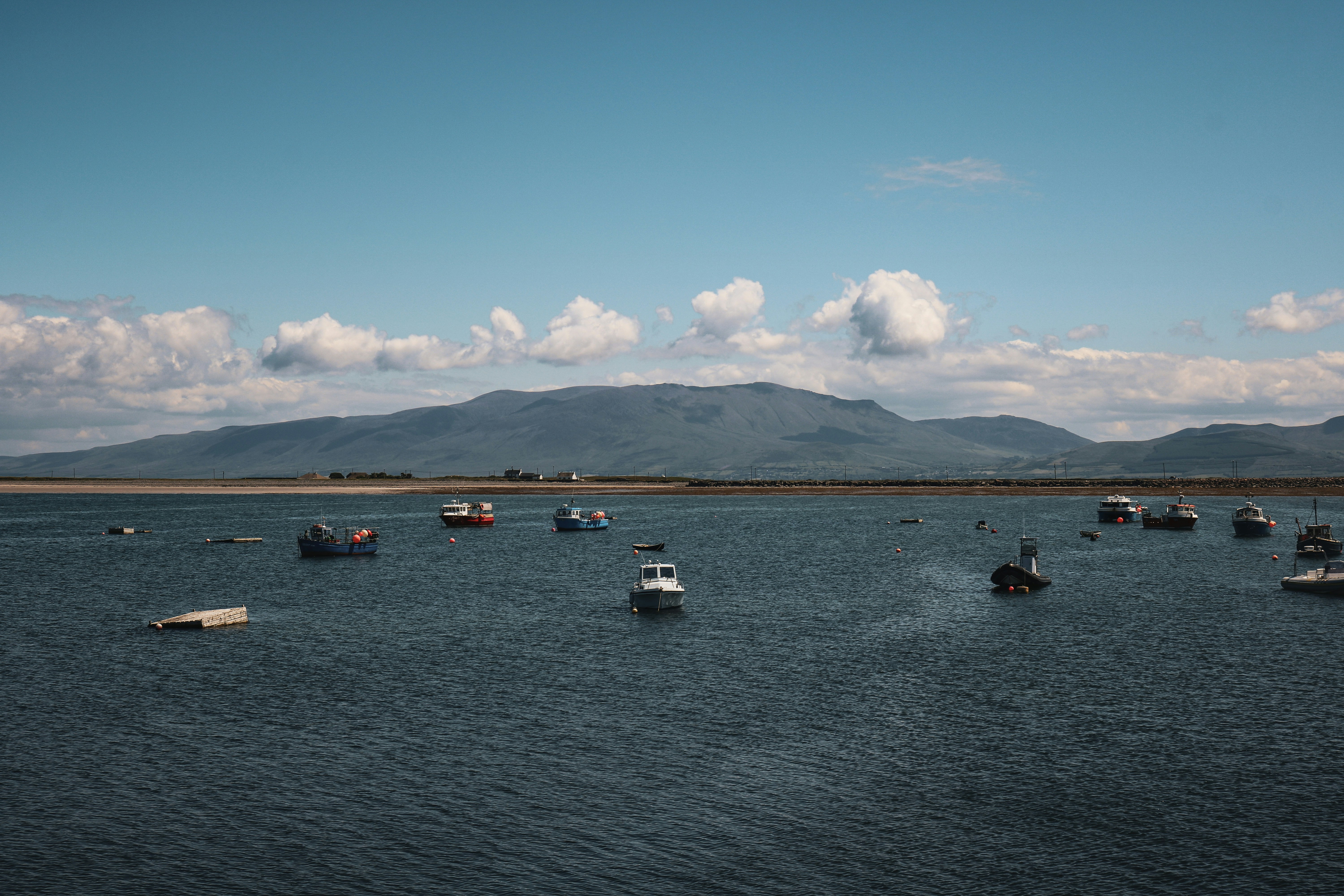 Barcos flutuam na água perto de uma montanha.