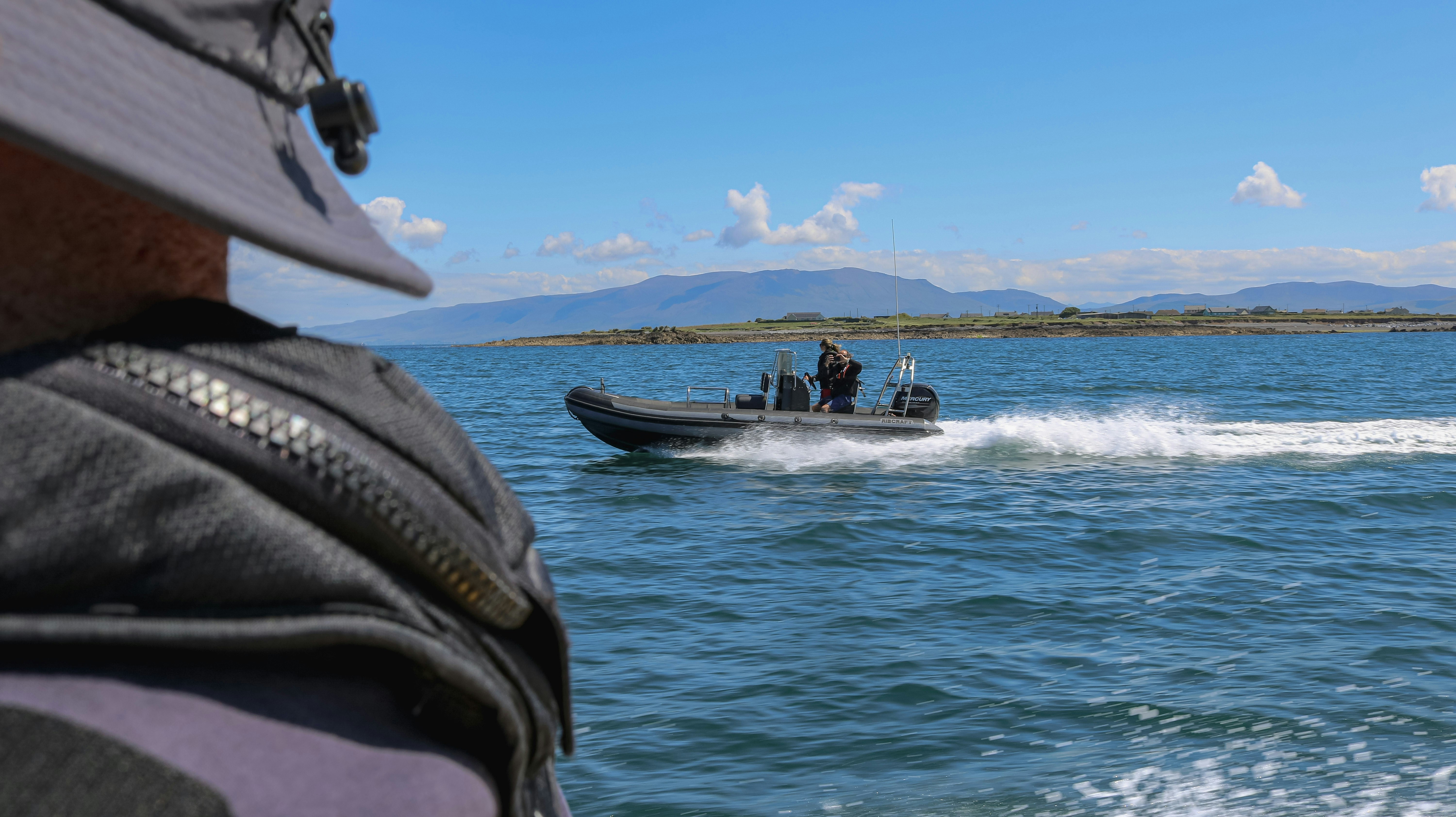 Homem observa uma lancha na água.
