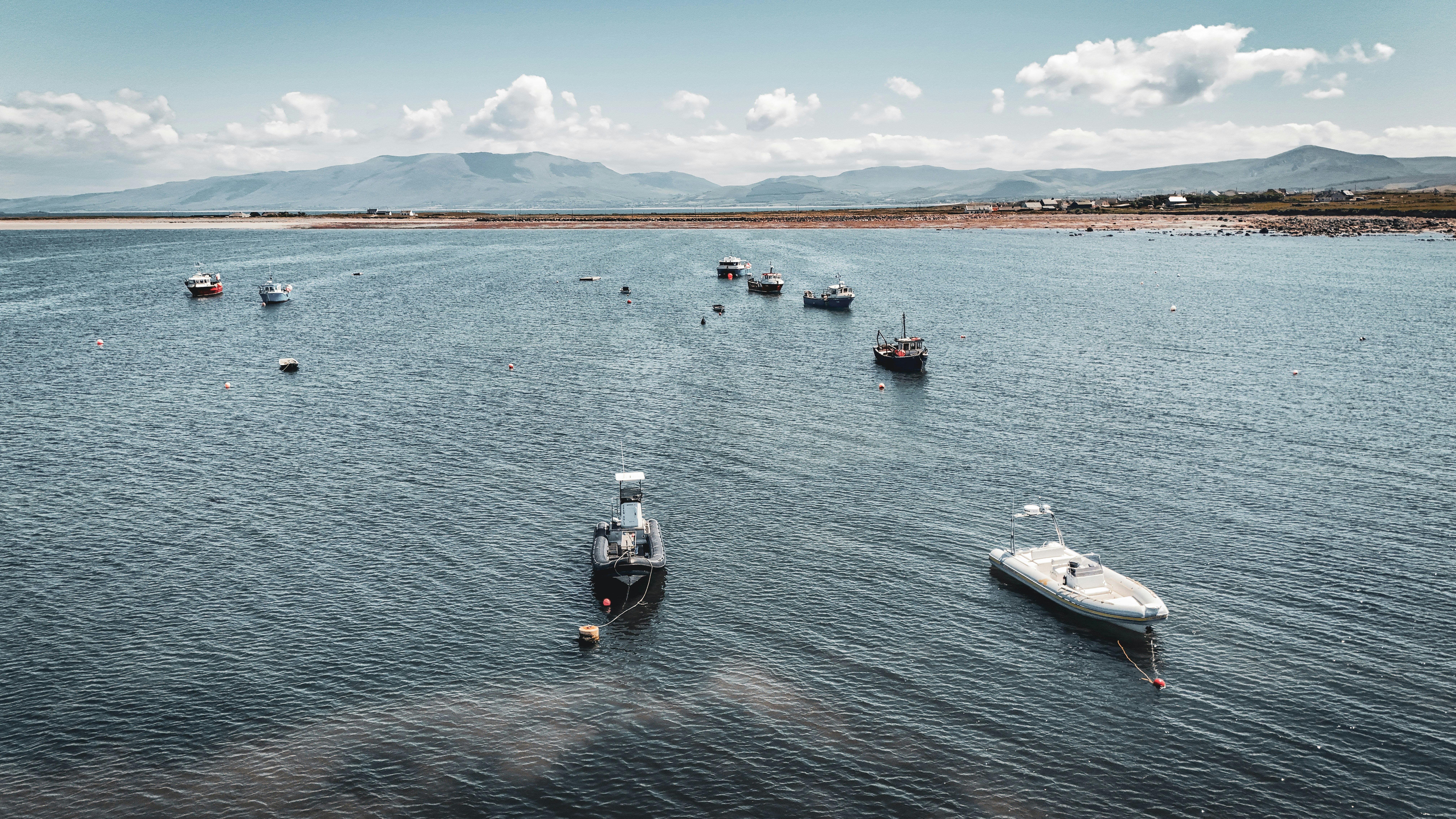 Barcos flutuam na água perto das montanhas.