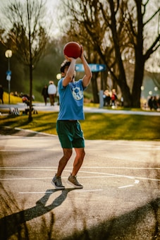 Man shoots a basketball outside in the park.