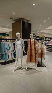 Clothing store display with mannequins and racks.