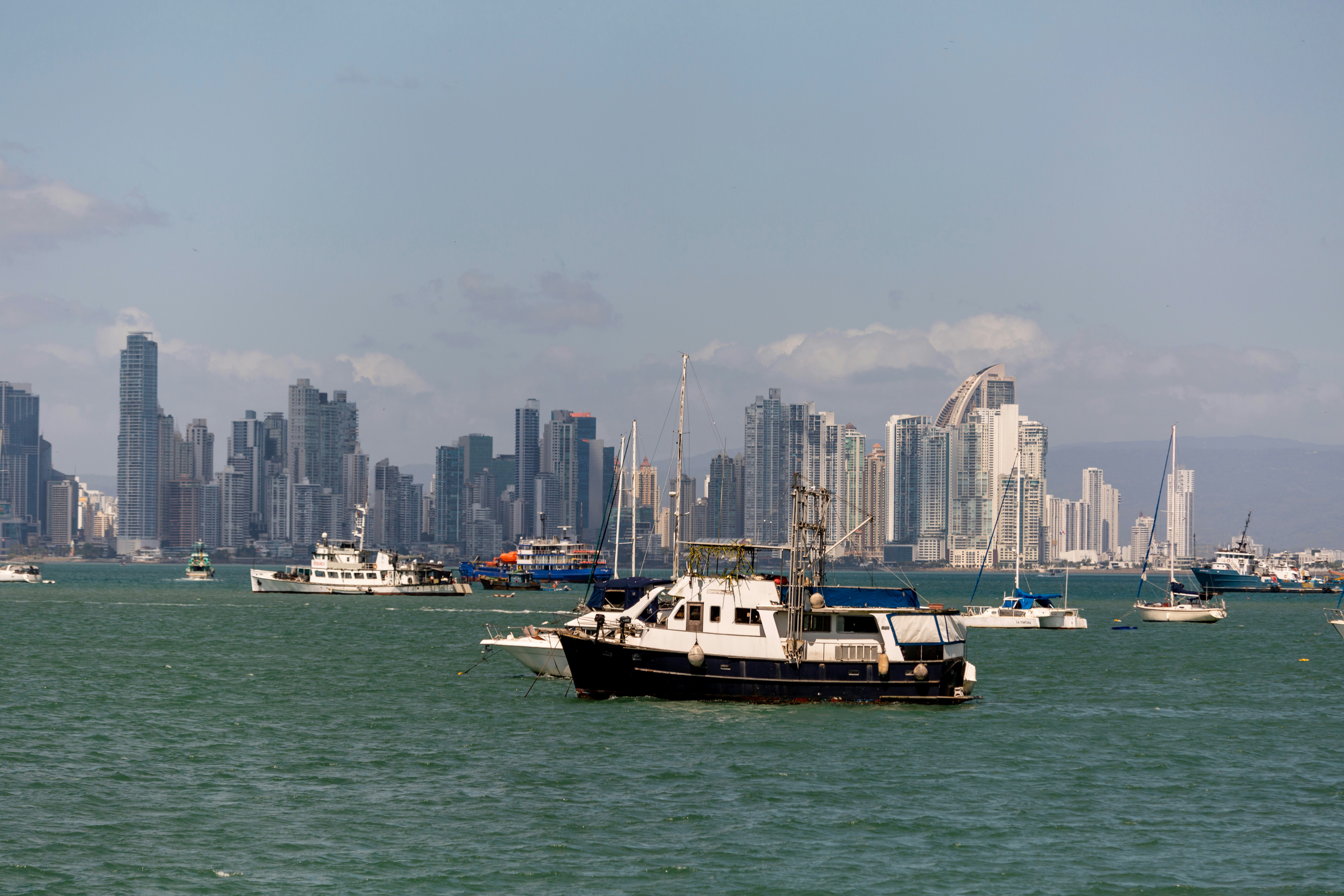 Boats on the water in front of a cityscape.