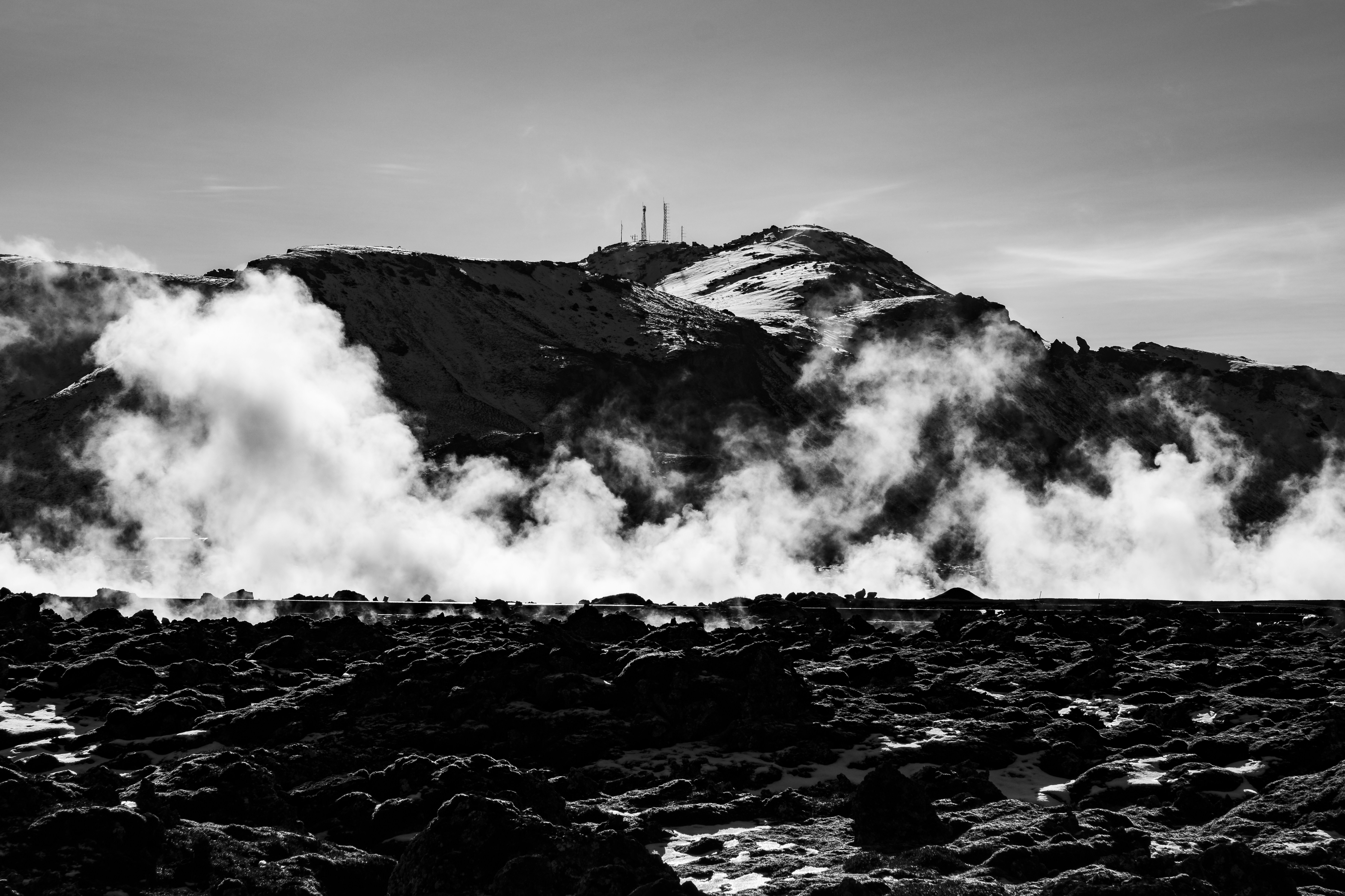 Steaming geysers in front of a mountain.