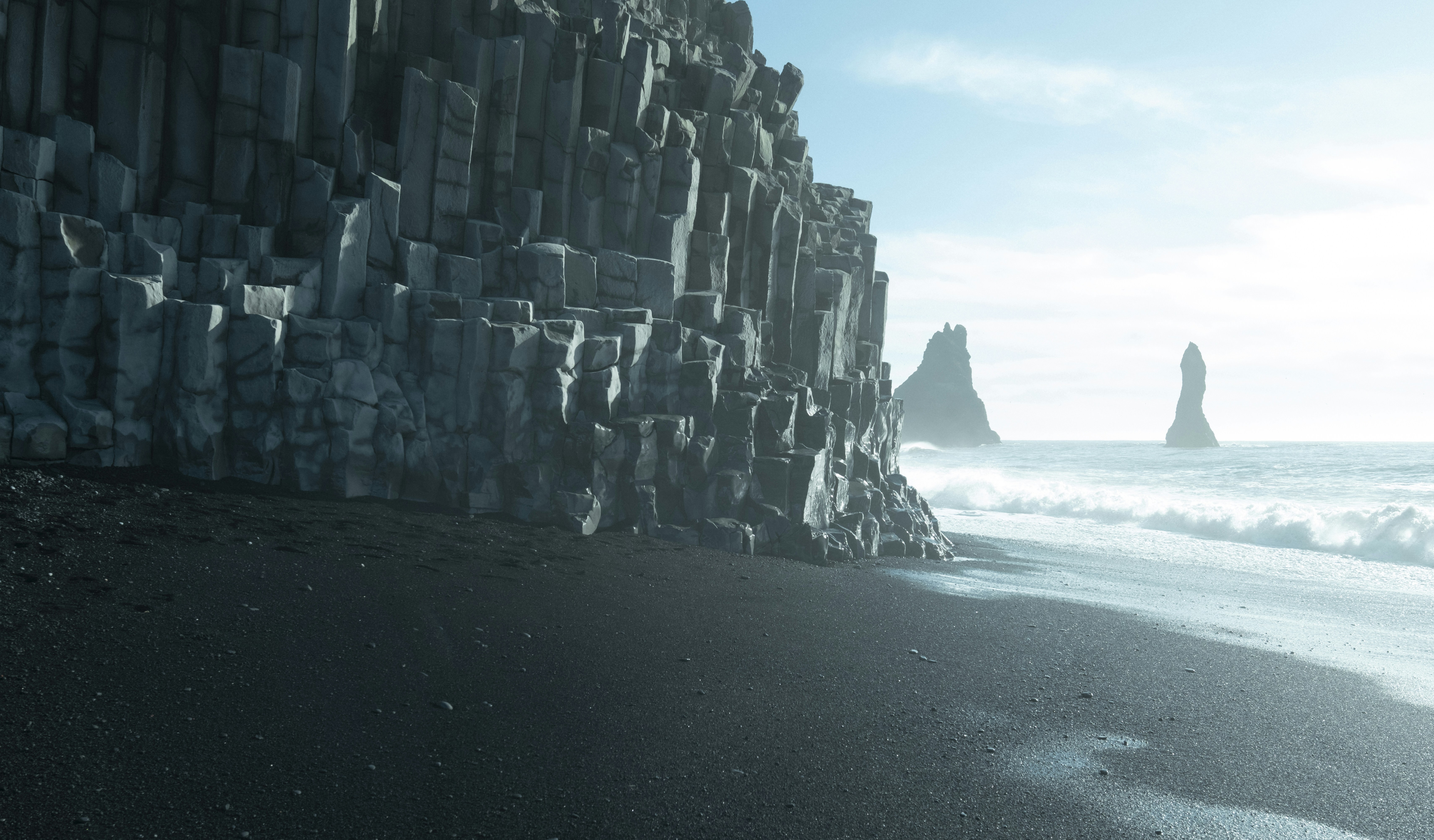 Black sand beach with striking rock formations.