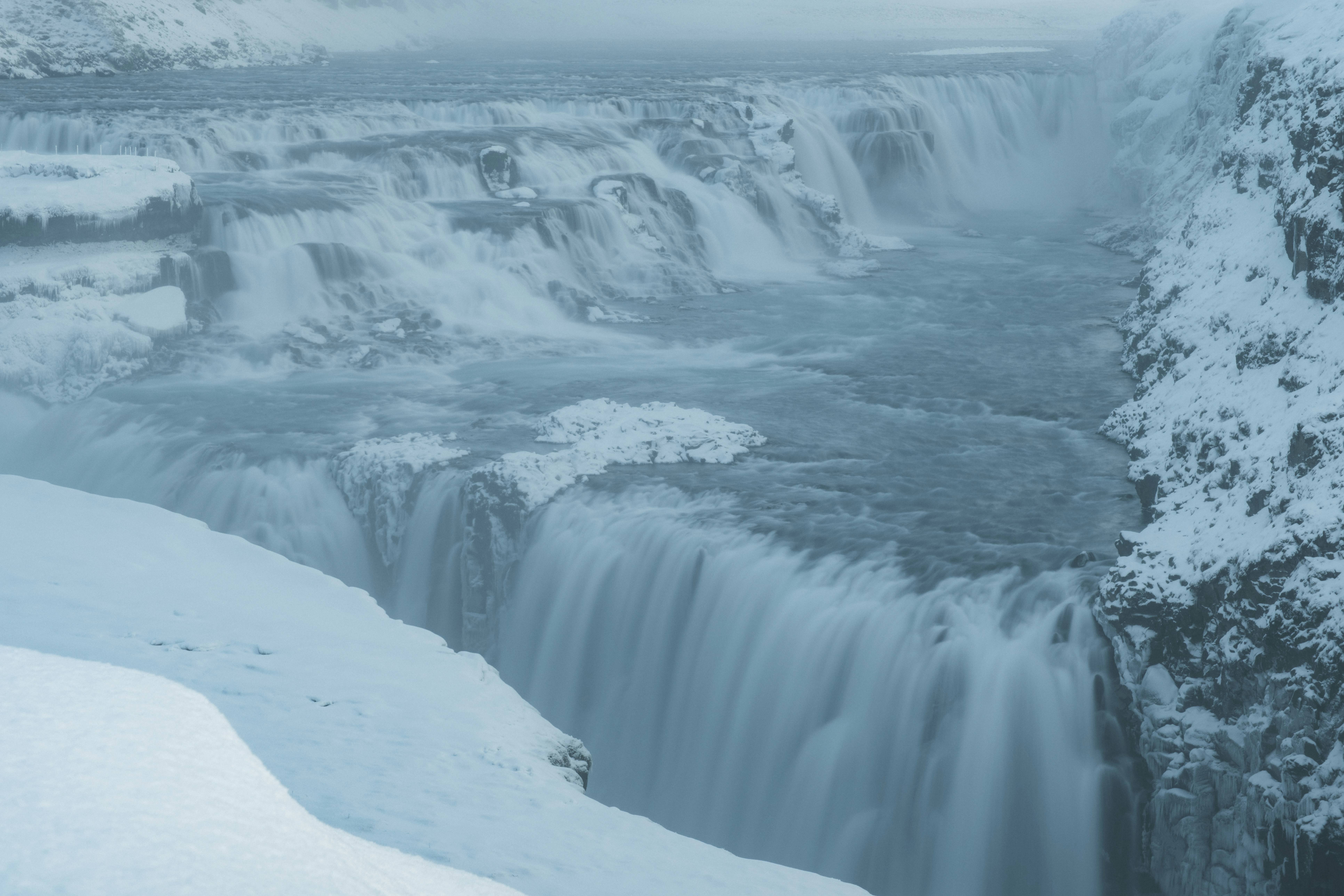 A snowy waterfall cascades down a rocky cliff.
