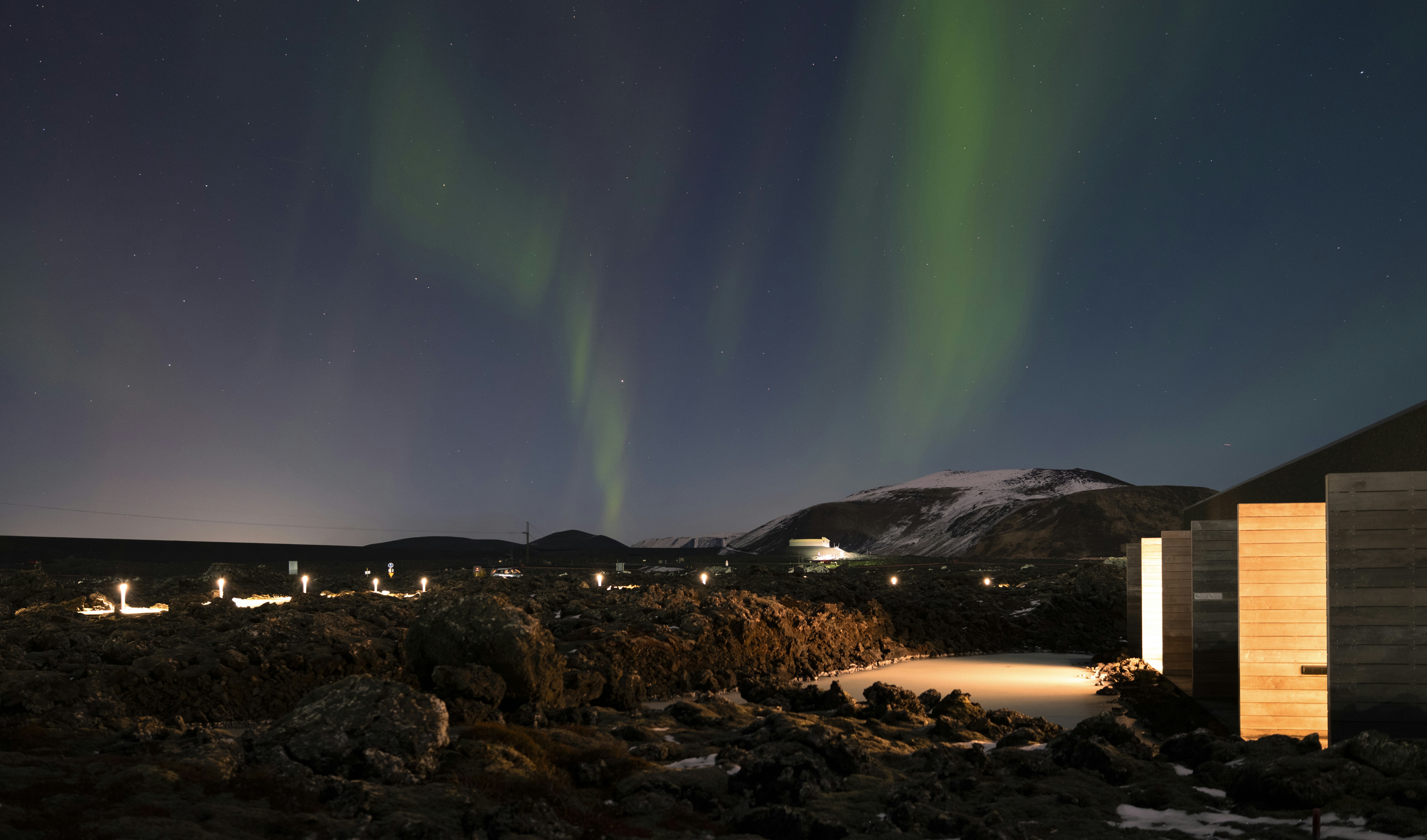 Aurora borealis dances over a cozy lodge.