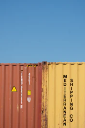 Shipping containers stand against a bright blue sky.