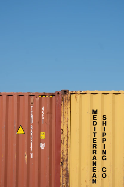 Shipping containers stand against a bright blue sky.