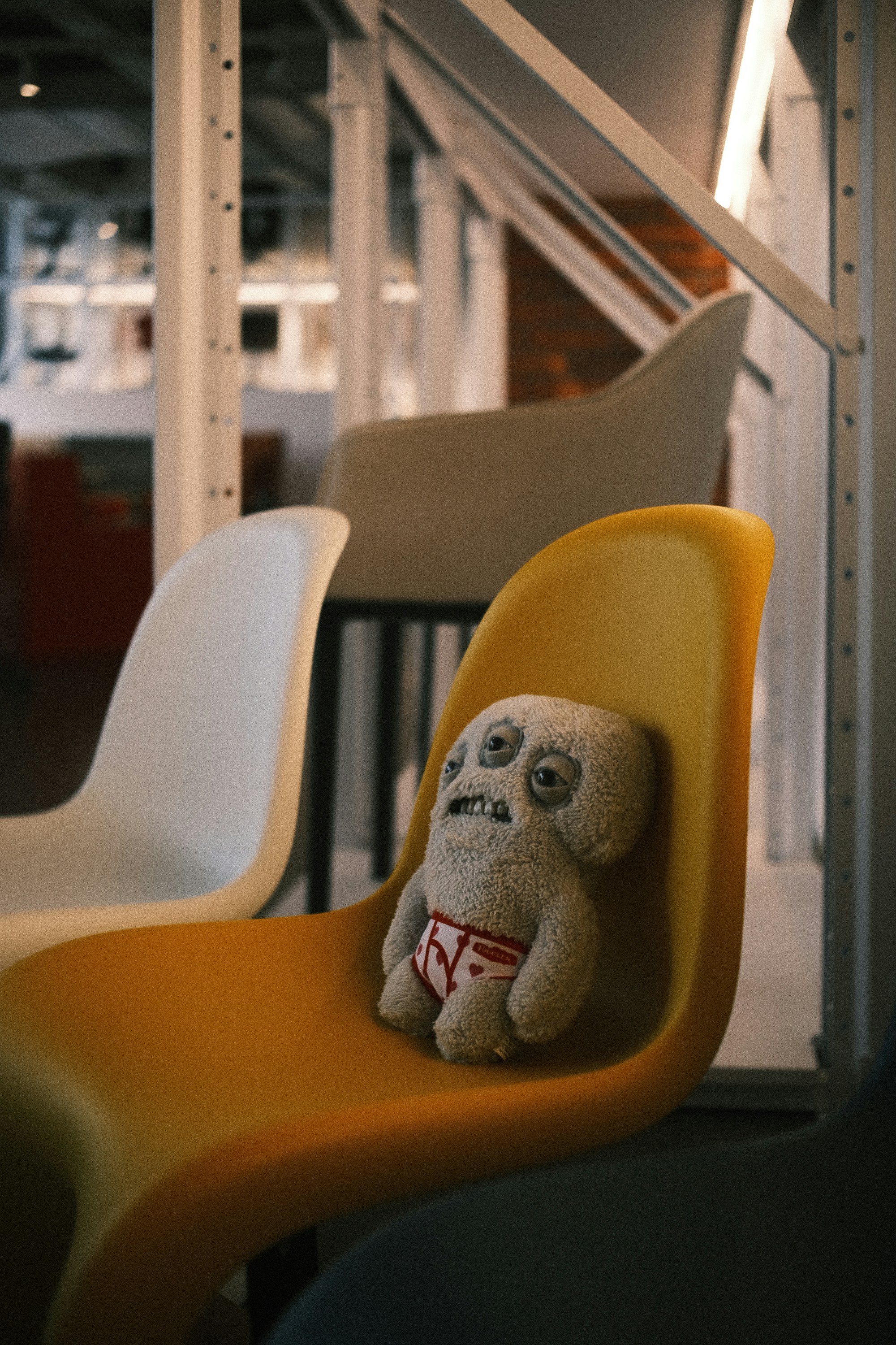 A strange doll sits in a brightly colored chair.