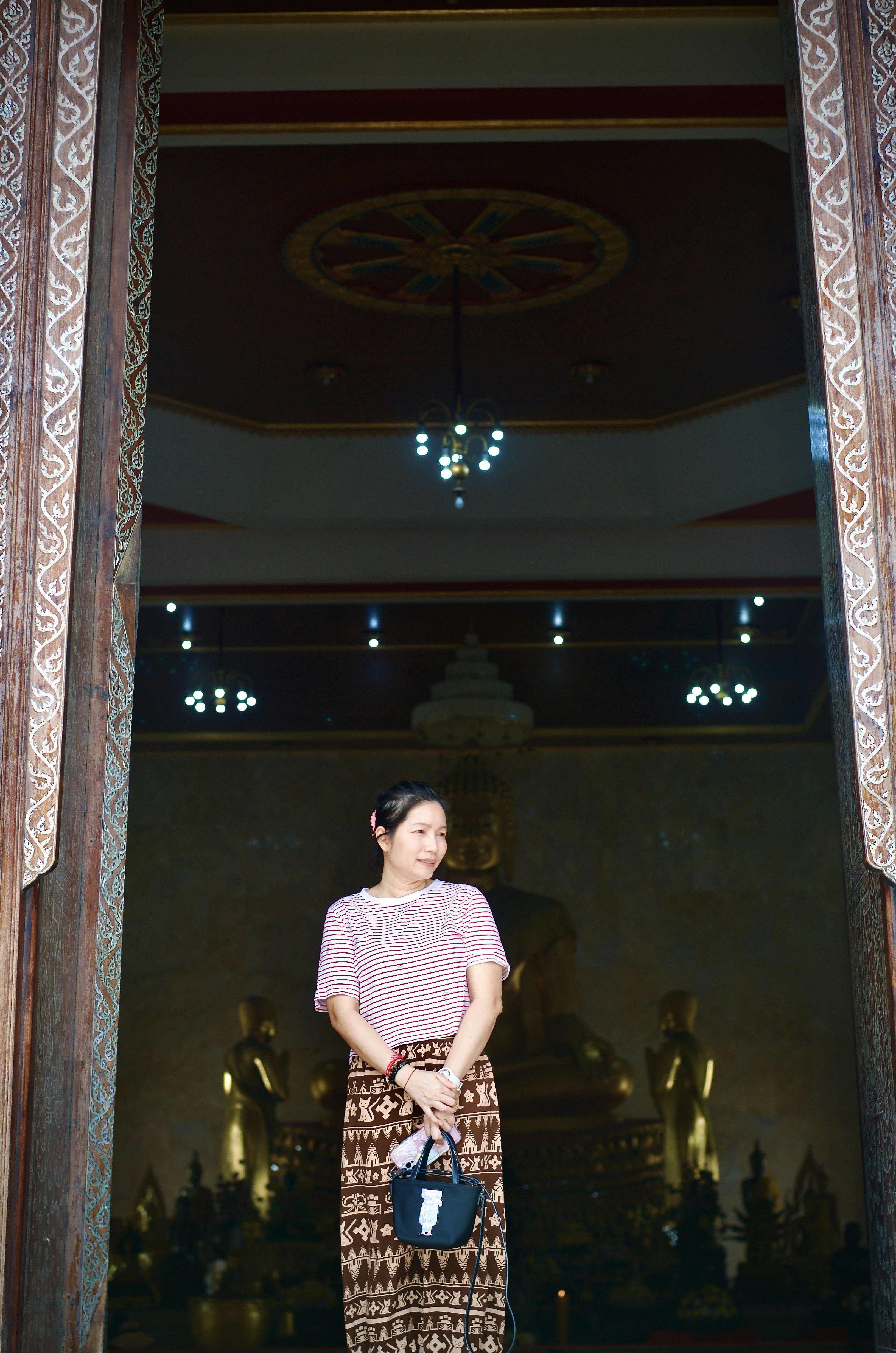 Woman poses in front of a temple doorway.