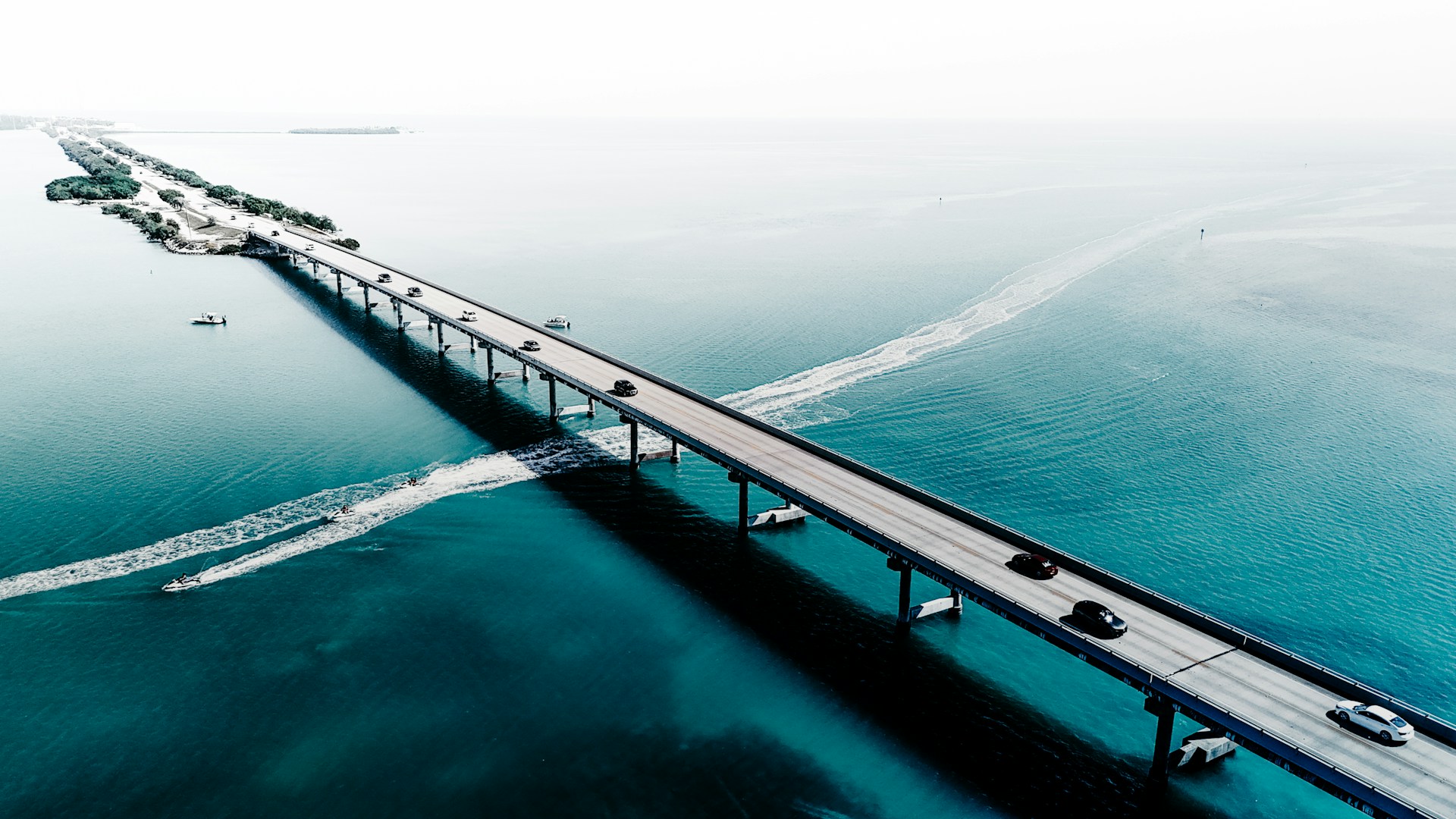 A bridge spans across the calm, blue ocean.