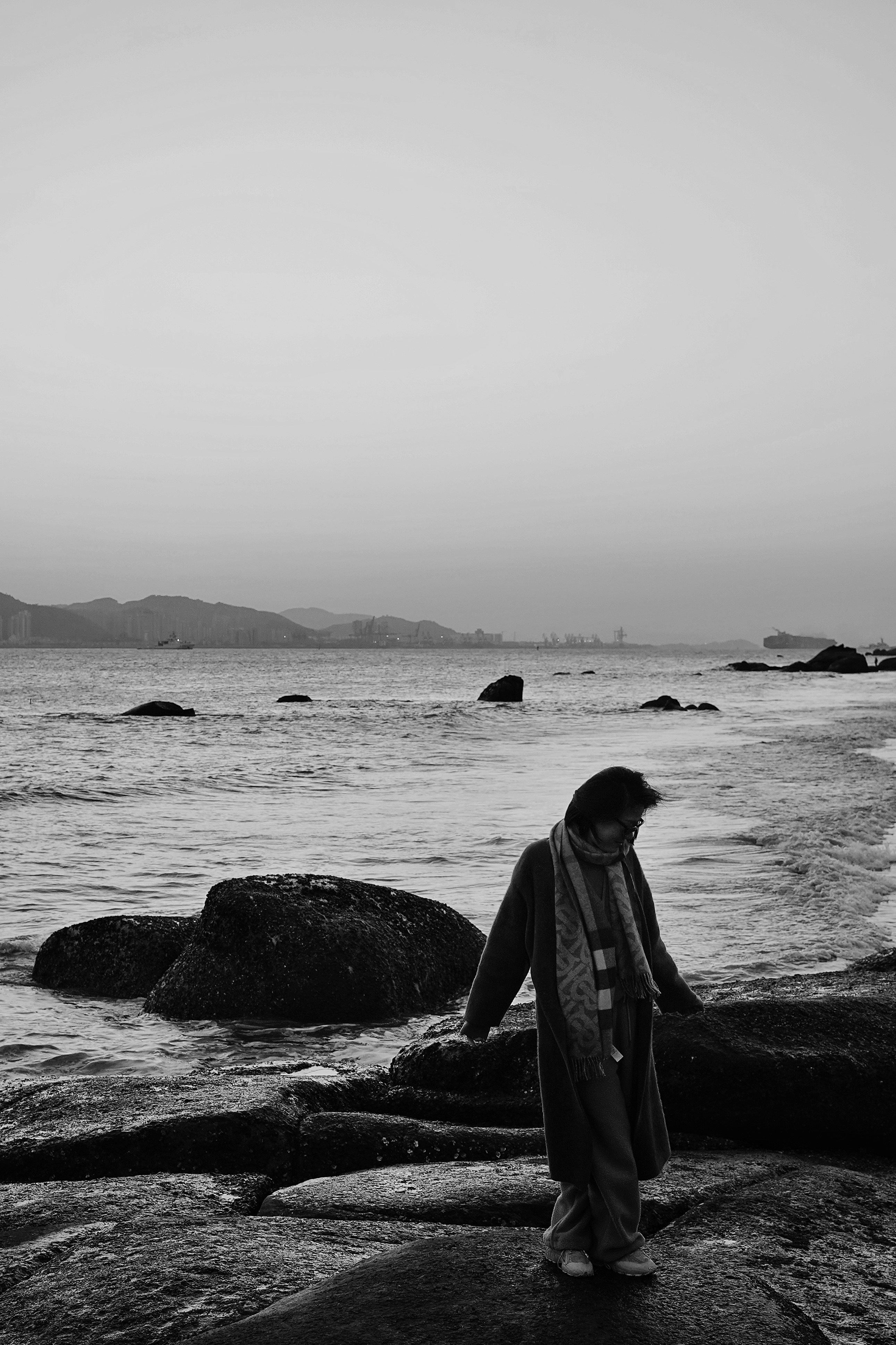 Una persona passeggia lungo una spiaggia rocciosa.