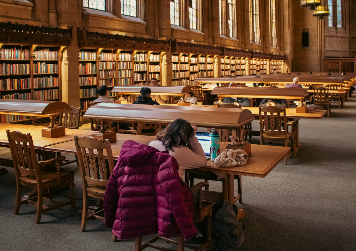A student studying with a laptop in a large university library