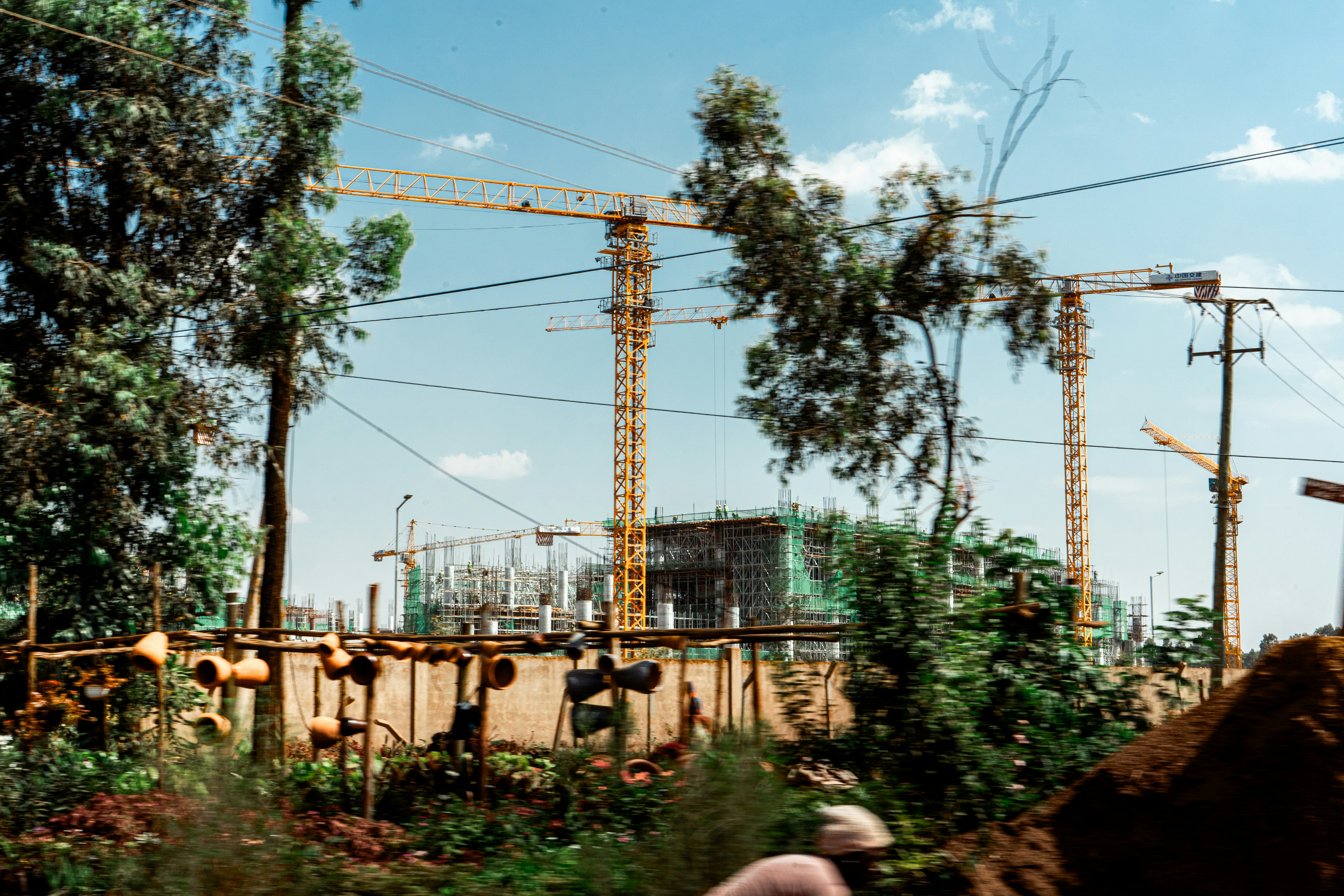 Construction site with cranes and trees is shown.