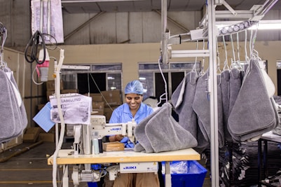 Woman sews items at a factory production line.