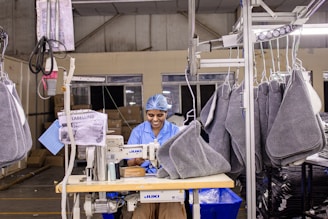 Woman sews items at a factory production line.