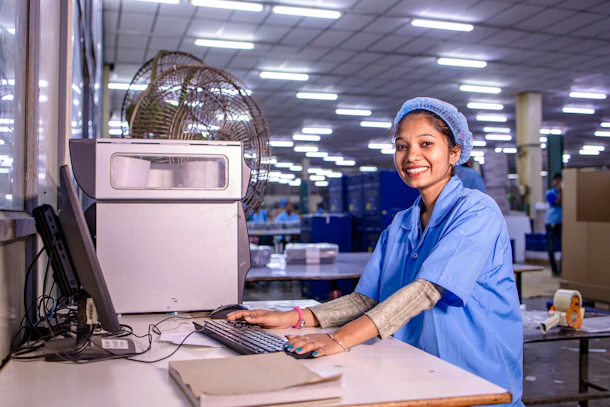 Woman works at computer in a factory.