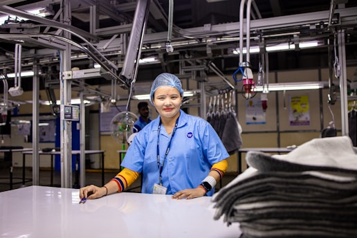 A smiling woman stands in a factory.