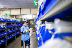 A woman works in an organized warehouse.