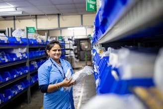 A woman works in a warehouse, smiling brightly.