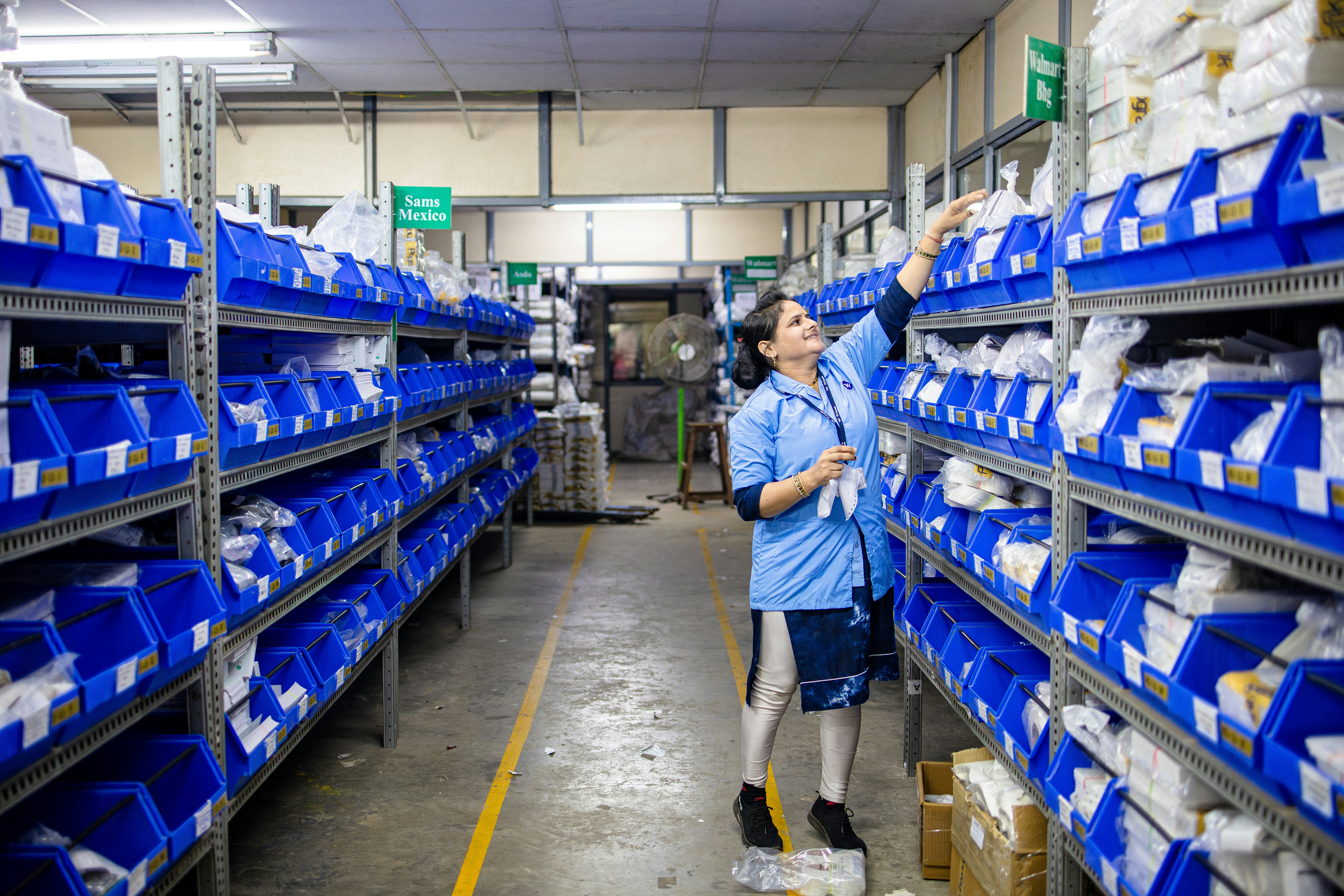 Worker is taking something from a shelf in a warehouse.