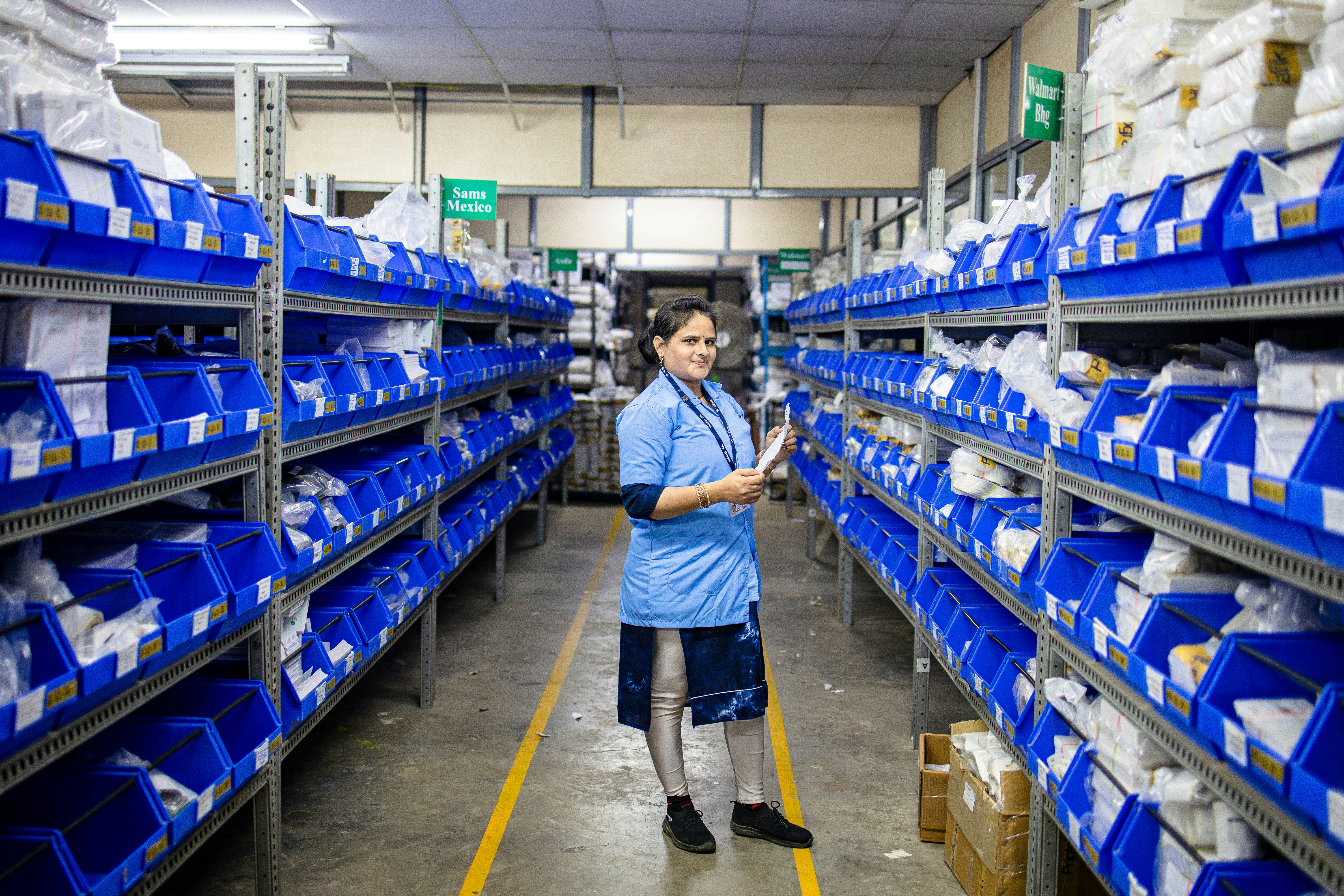 A worker stands in a warehouse filled with supplies.
