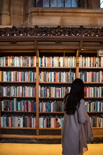 Woman browses a library's vast shelves of books.