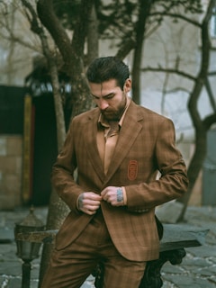 Man in suit buttons his jacket outdoors.