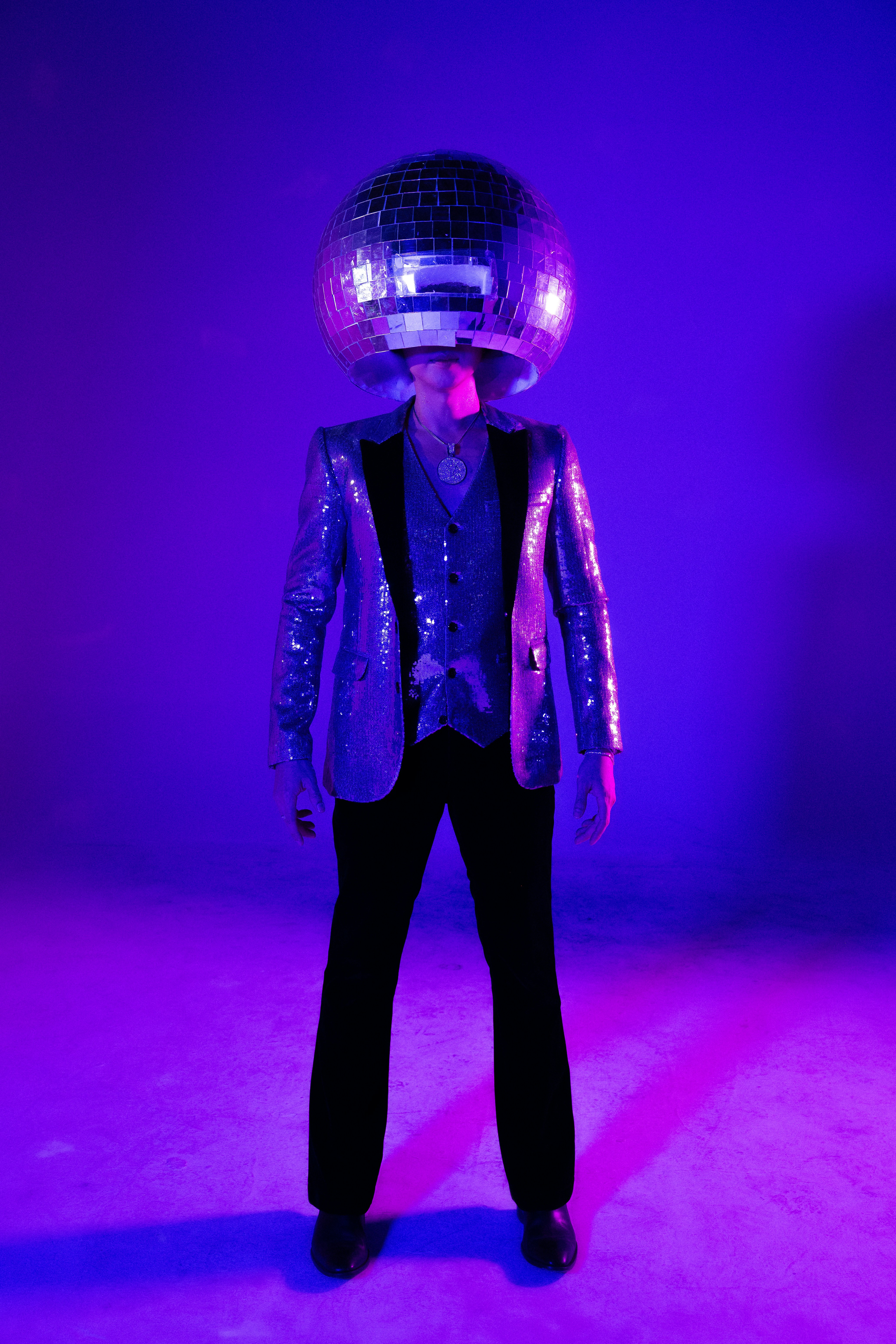 Une personne porte une boule disco en guise de tête.