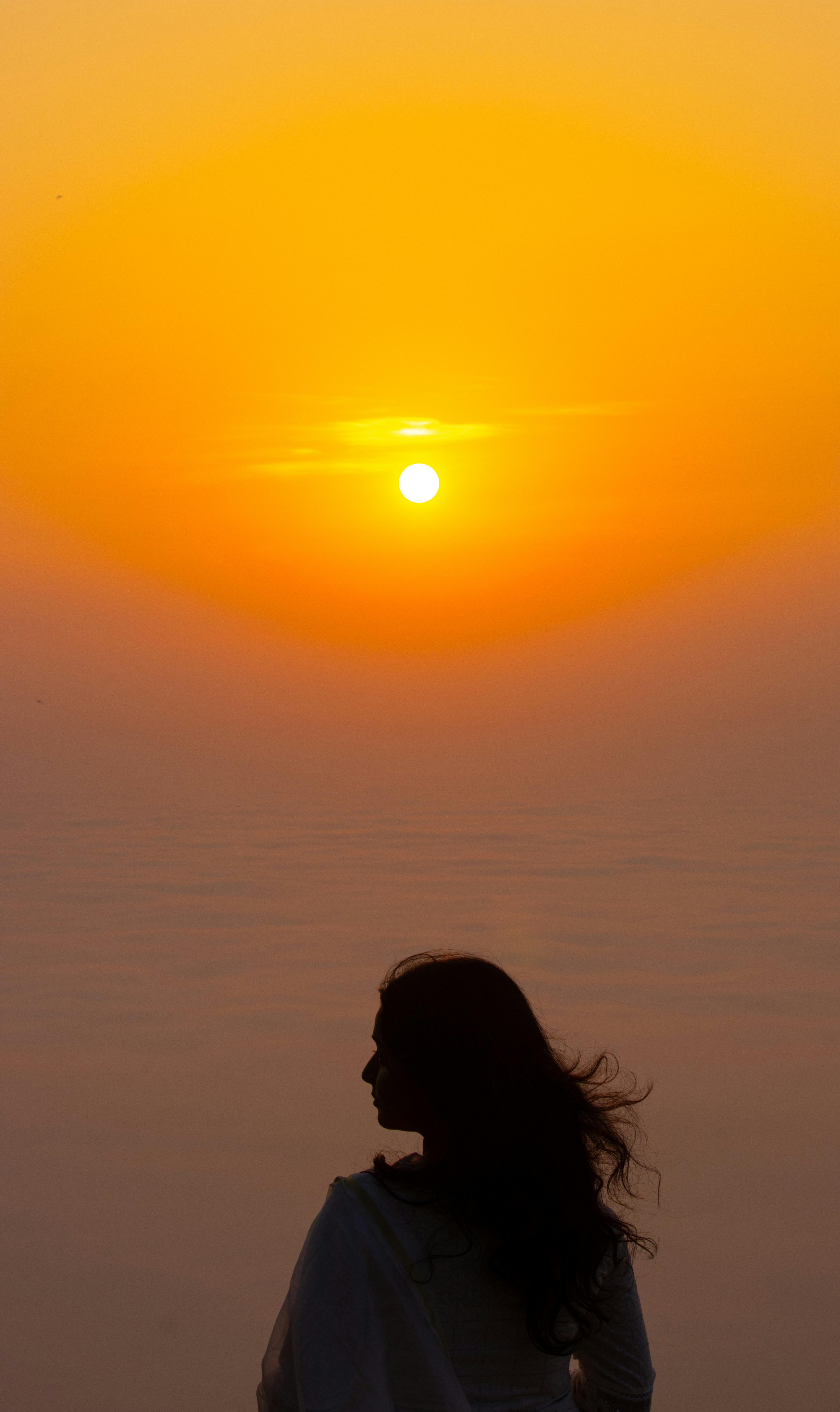 Silhouette of a woman watches the sunrise.