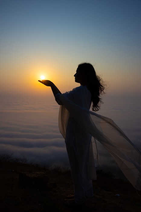 Woman holds the sun in her hand at sunrise.