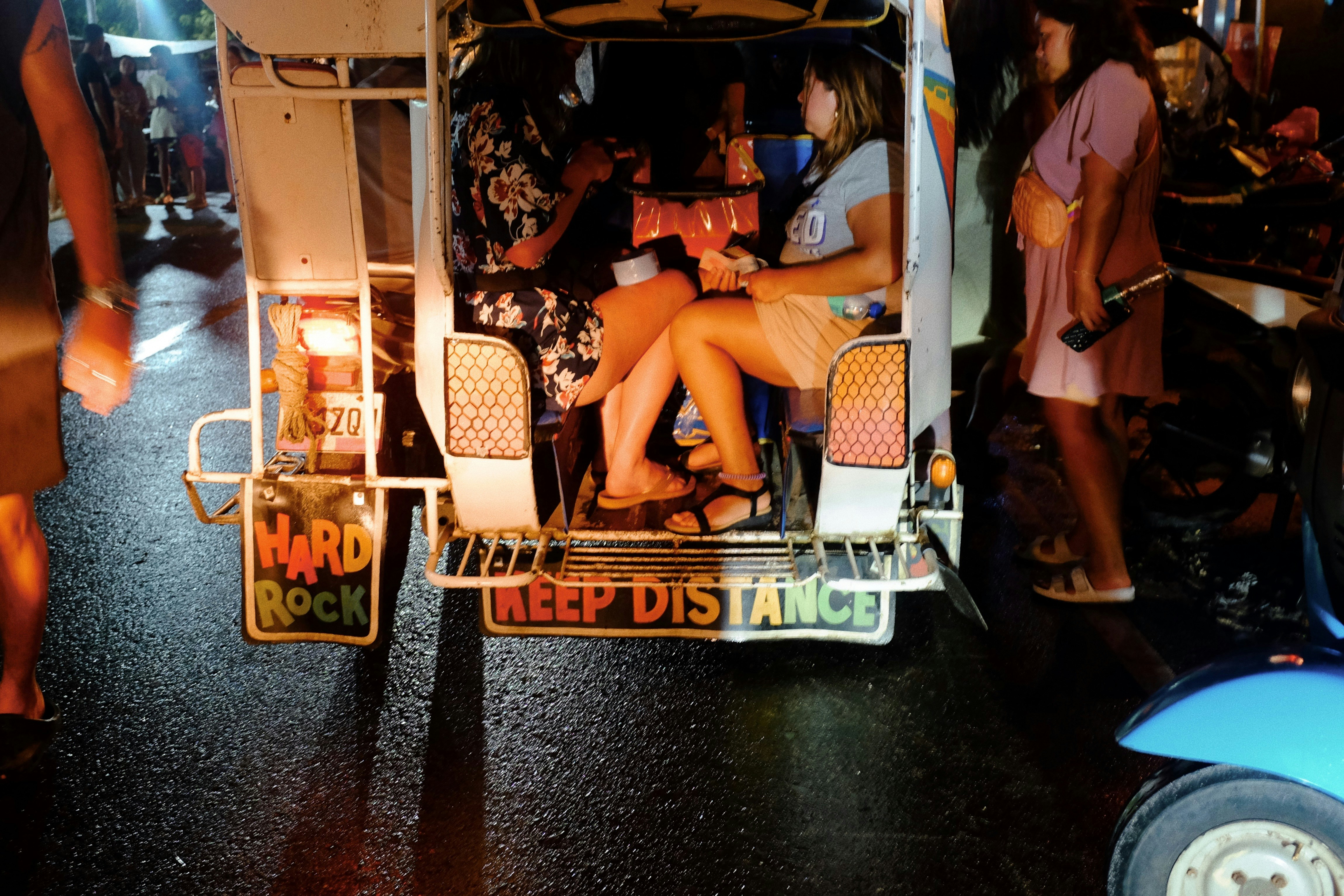 Eine Frau fährt ein hell erleuchtetes Tuk-Tuk.