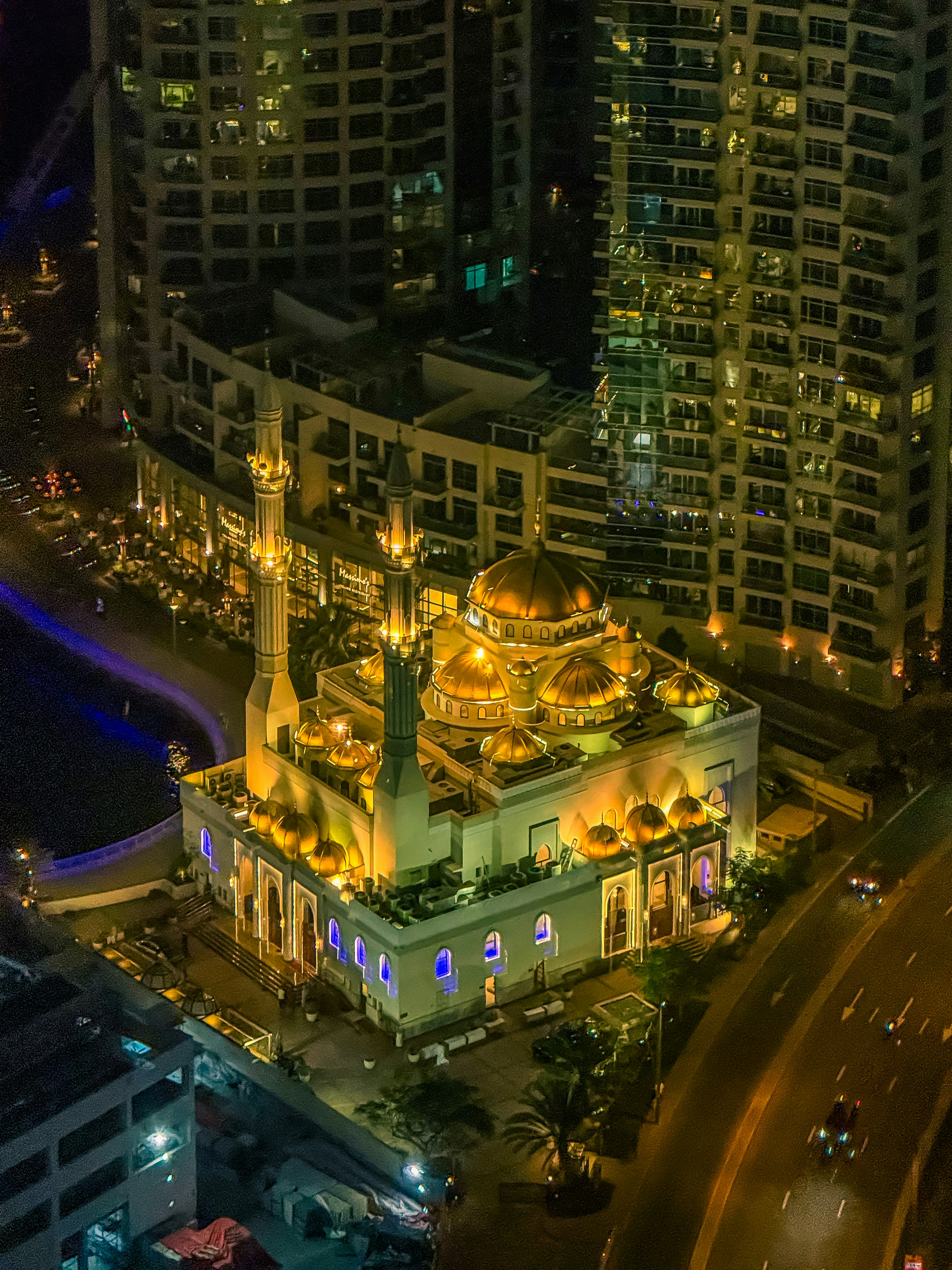 A lit-up mosque shines brightly at night.