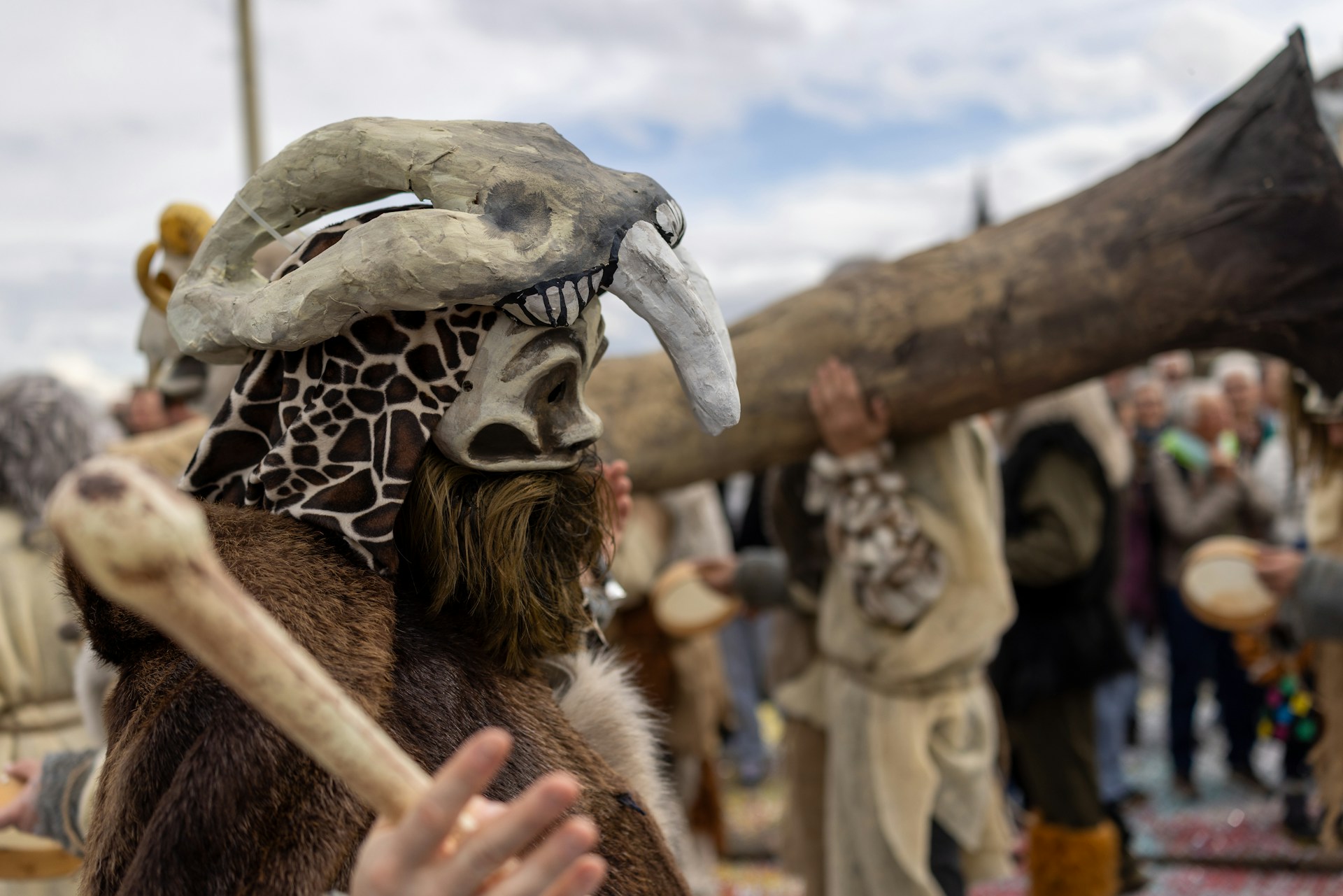 A person is wearing a mask and carrying a bone.