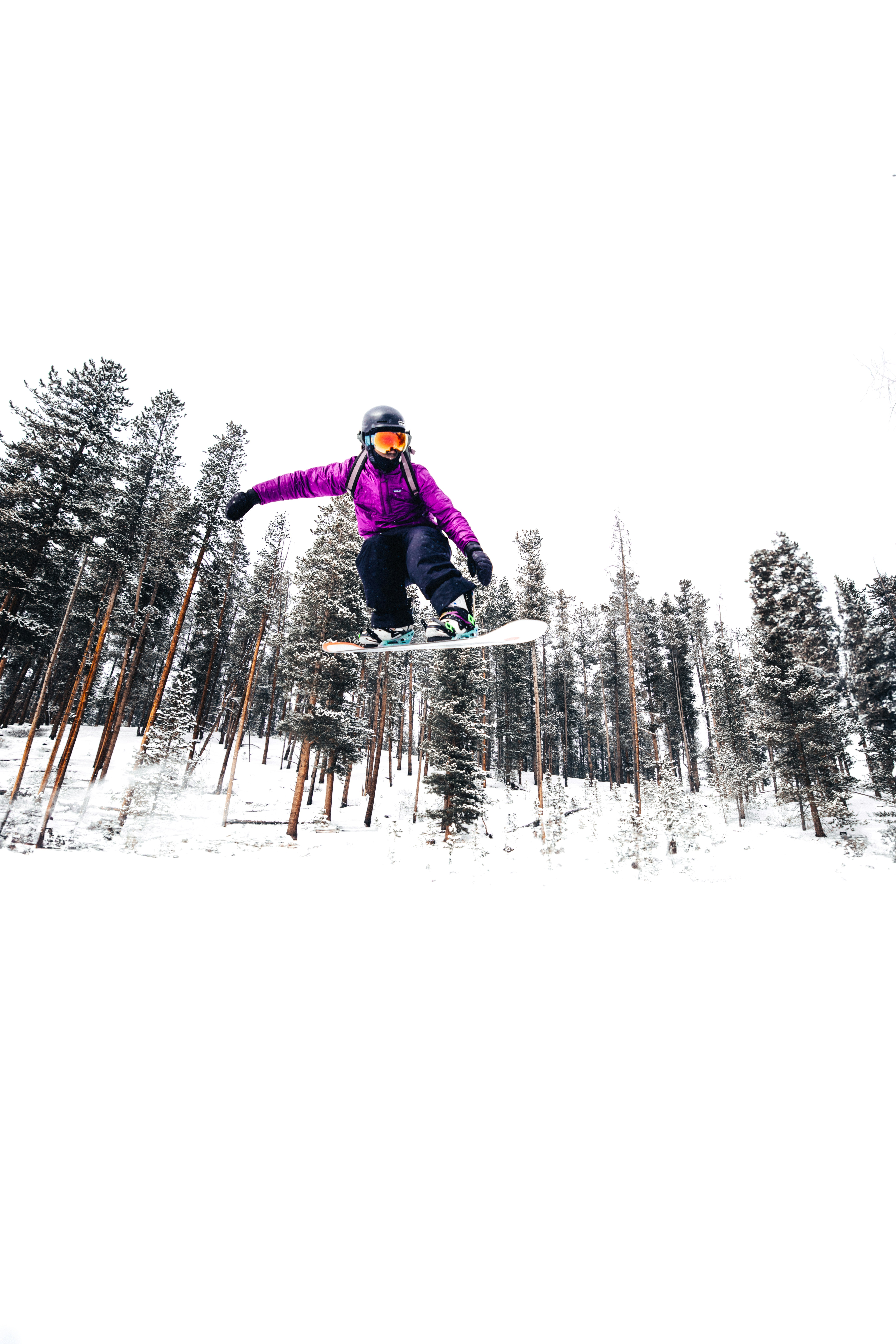 Snowboarder doing an aerial trick over a snowy landscape.