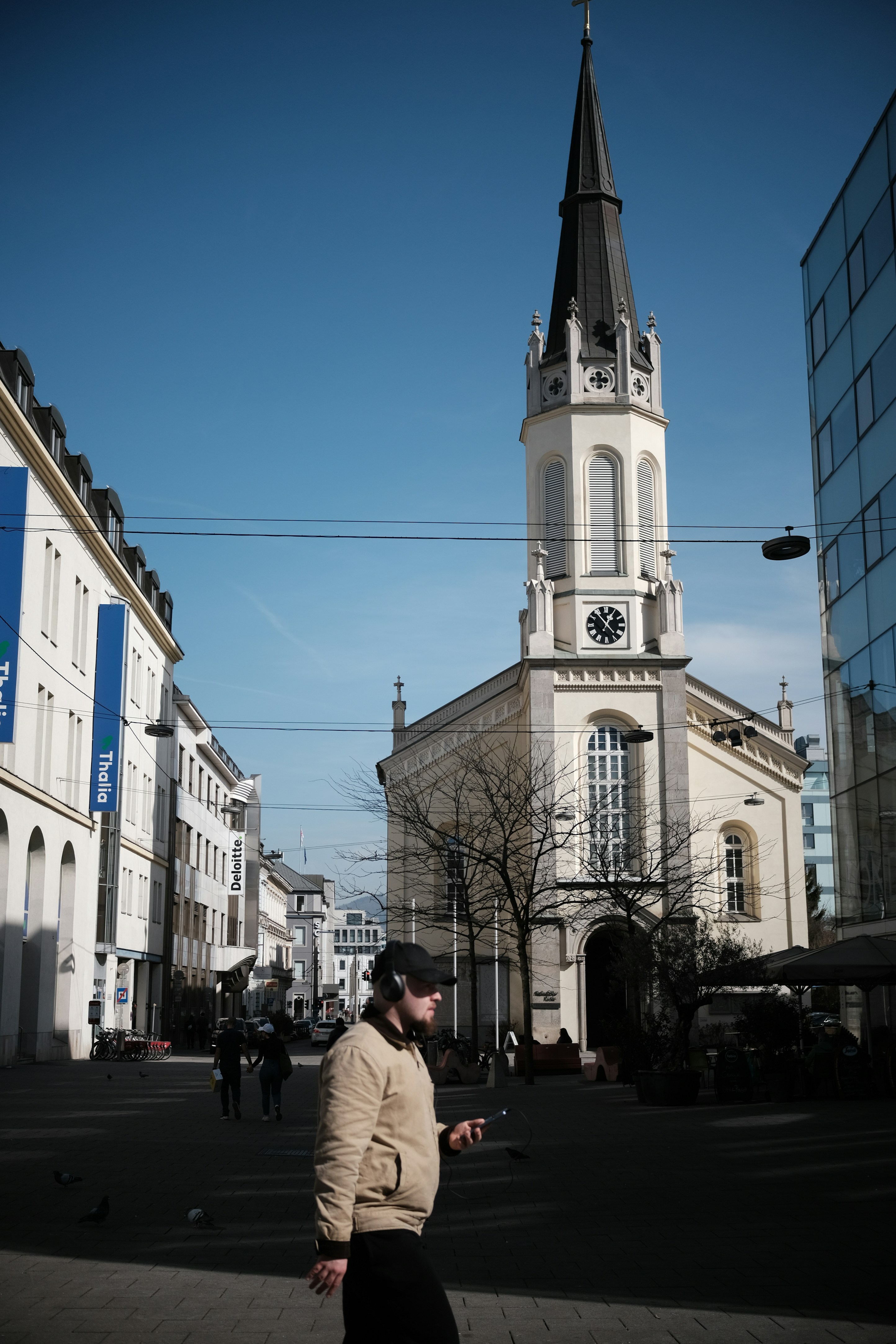 Mann geht in der Nähe einer Kirche auf einer sonnigen Straße spazieren