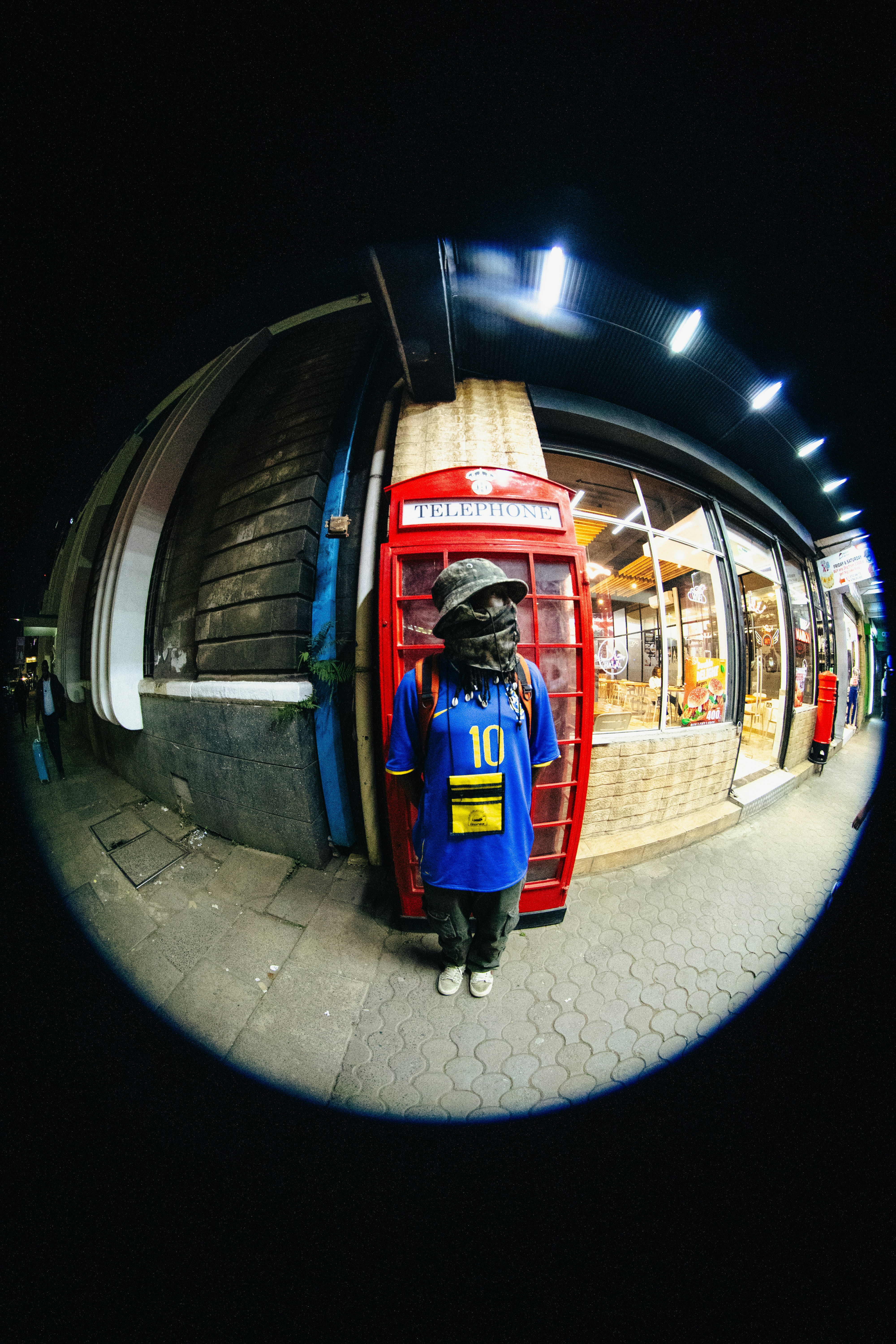 A mannequin stands near a red telephone booth.