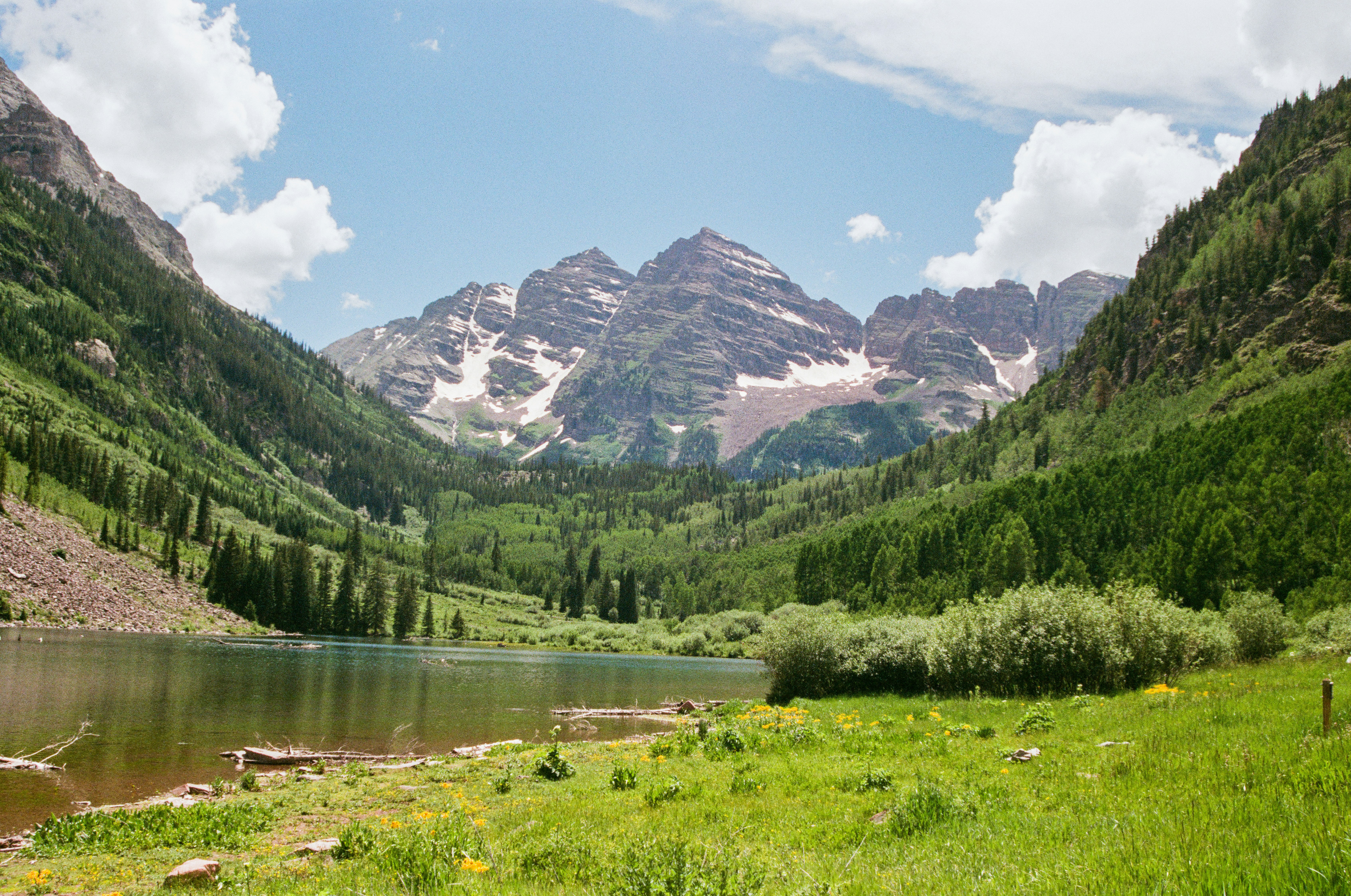 Mountains and lake meet under a sunny sky.