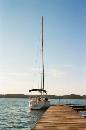 A sailboat is docked at the end of a pier.